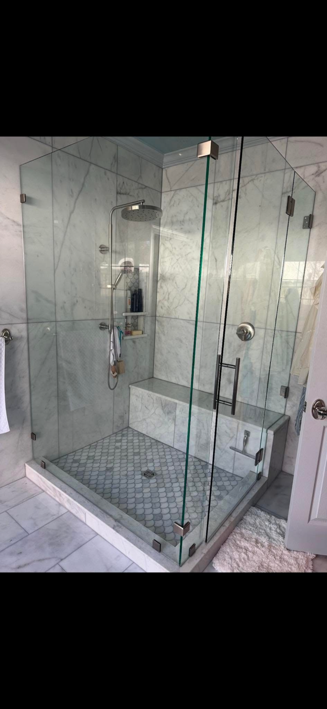 Chrome shower head spraying water in a tiled bathroom Chrome shower head spraying water in a tiled bathroom