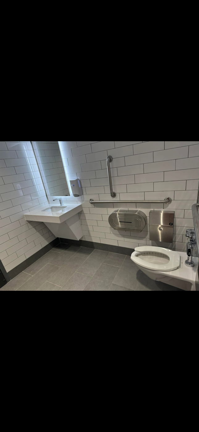 Hands using a red wrench to tighten a bathroom sink drain pipe under a sink Hands using a red wrench to tighten a bathroom sink drain pipe under a sink
