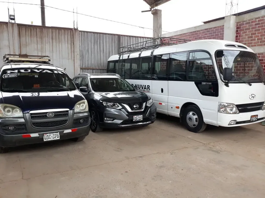 Tres vehículos estacionados, entre ellos dos todoterrenos y un minibús blanco, en un aparcamiento cubierto.