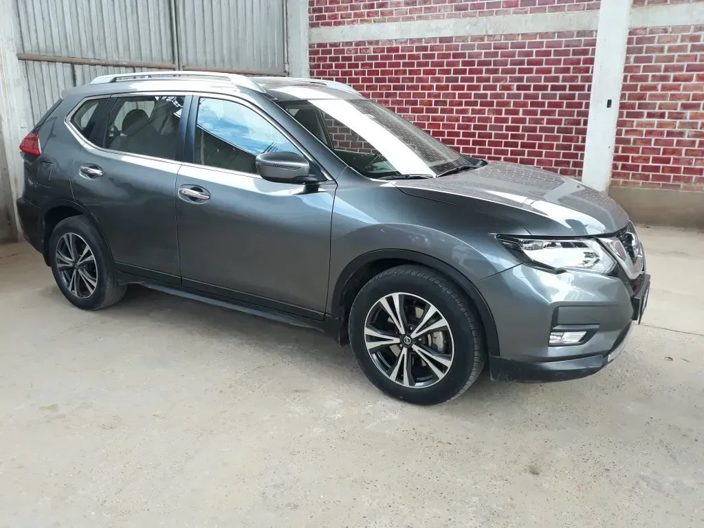Un SUV gris estacionado junto a un muro de ladrillos en un estacionamiento al aire libre.