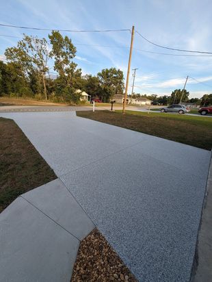 Gravel path curving through a grassy roadside area with trees, utility pole, and parked cars at dusk