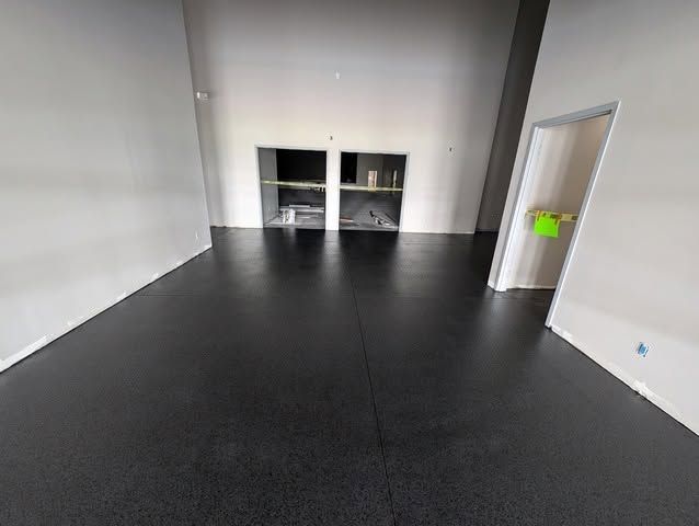 Empty room with black floor, white walls, and a small built-in cabinet at the back