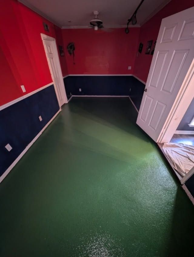 Empty room with red and navy walls, green floor, and white doors opened inward