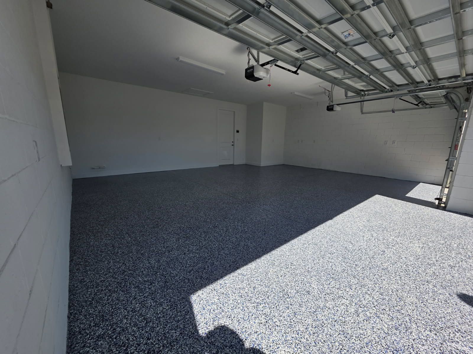 Empty garage interior with gray gravel floor and a partially open garage door.