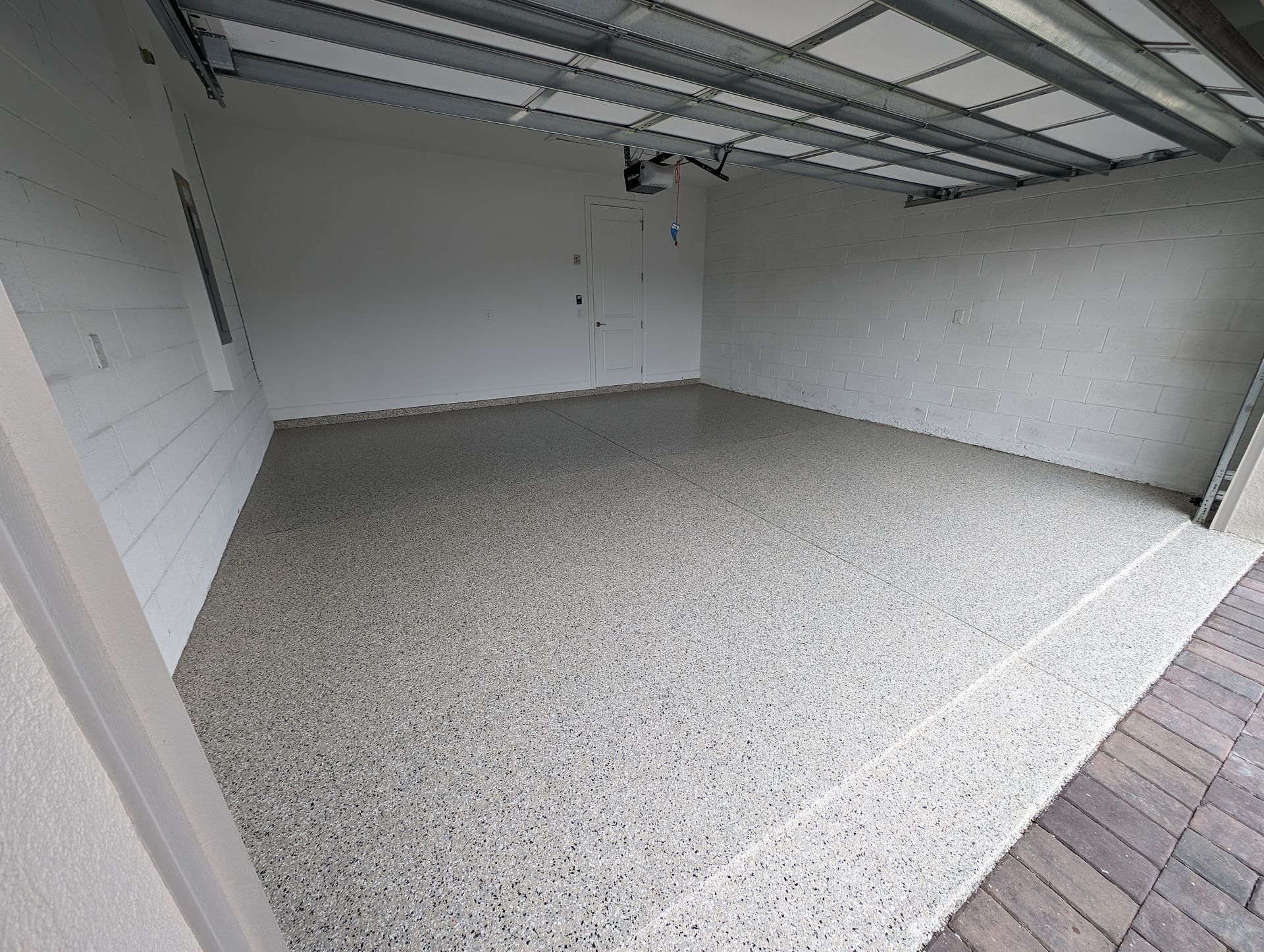 Empty garage with white walls, gray speckled floor, and open overhead door tracks