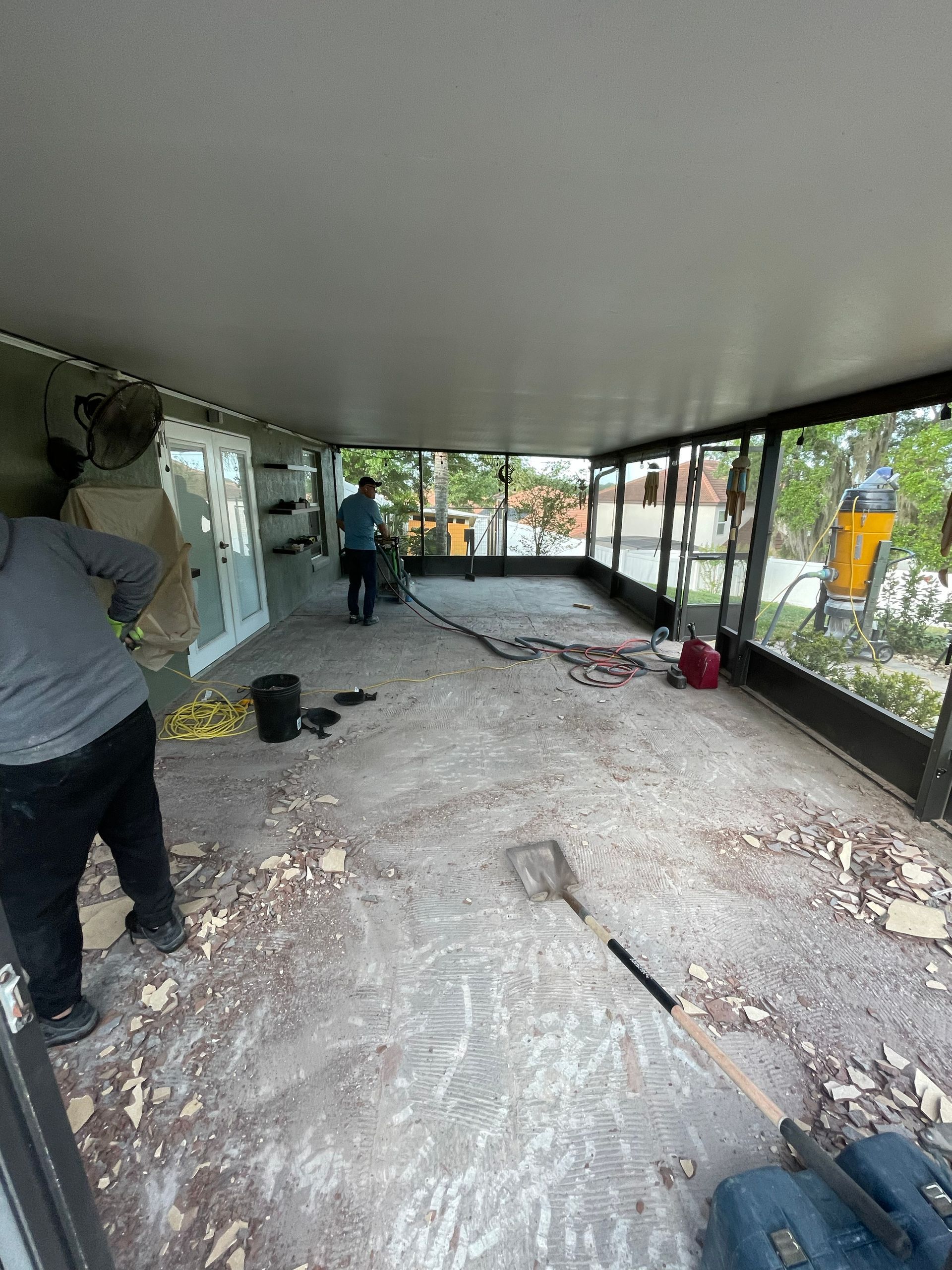 Person working on a covered patio renovation with debris and tools scattered across the floor