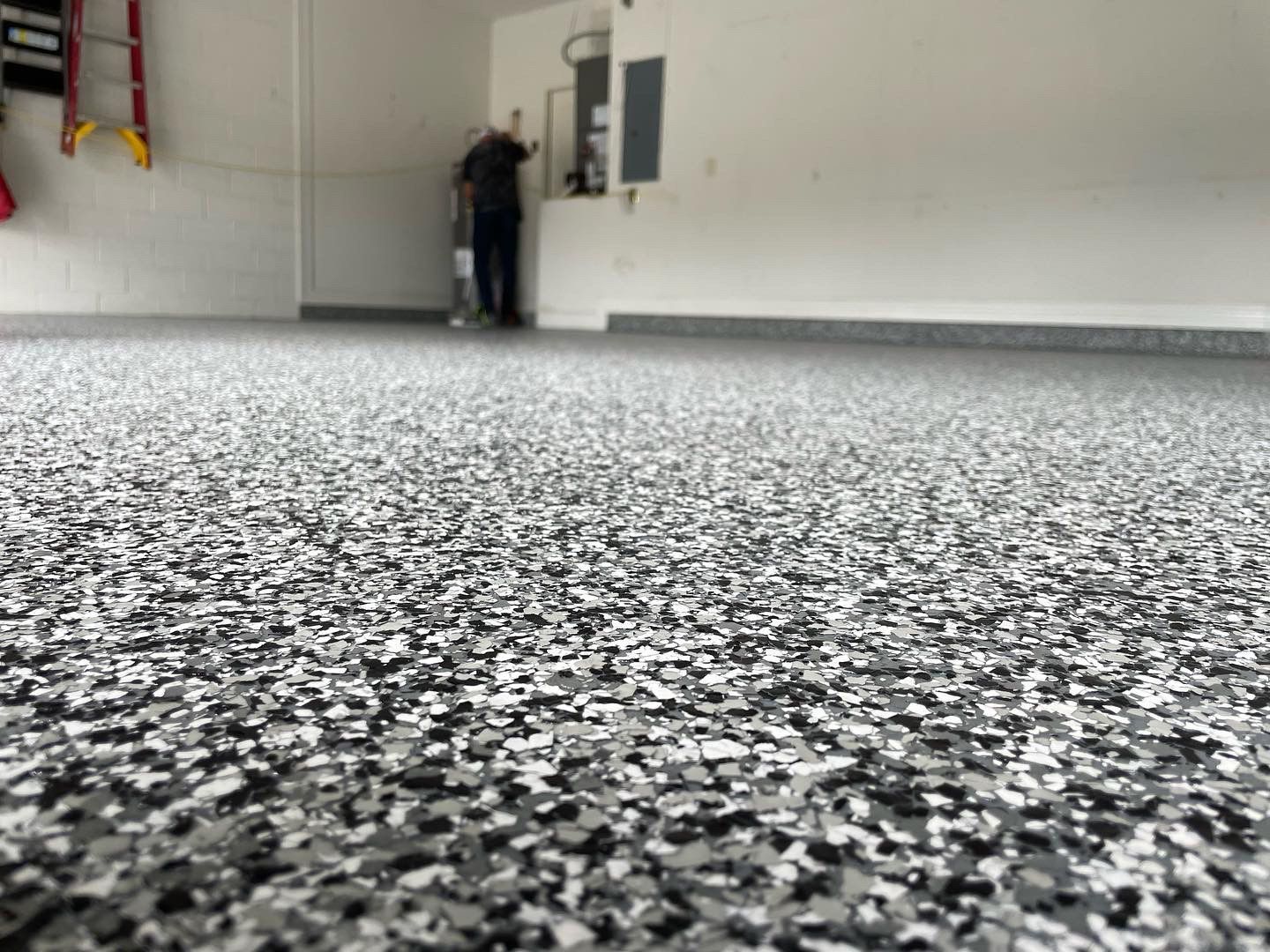 Two people standing in a bare room with a speckled gray floor