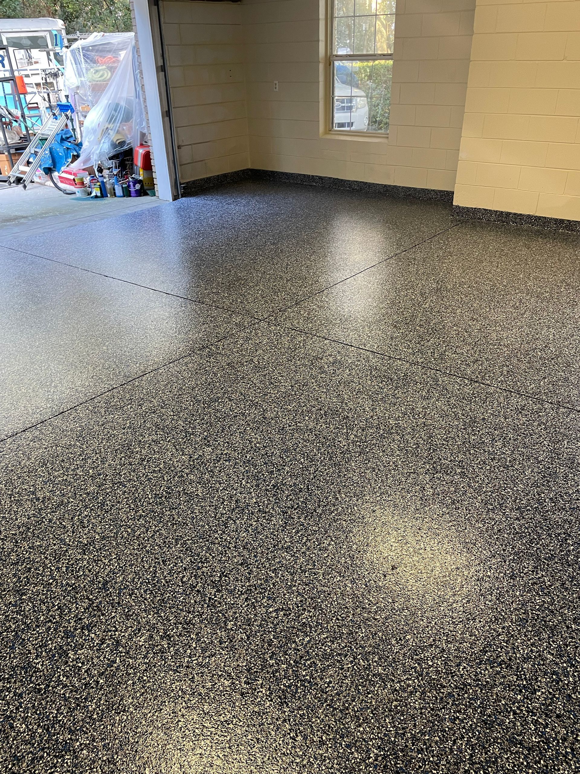 Speckled black-and-white epoxy floor in a garage or entryway with open doorway to the outside