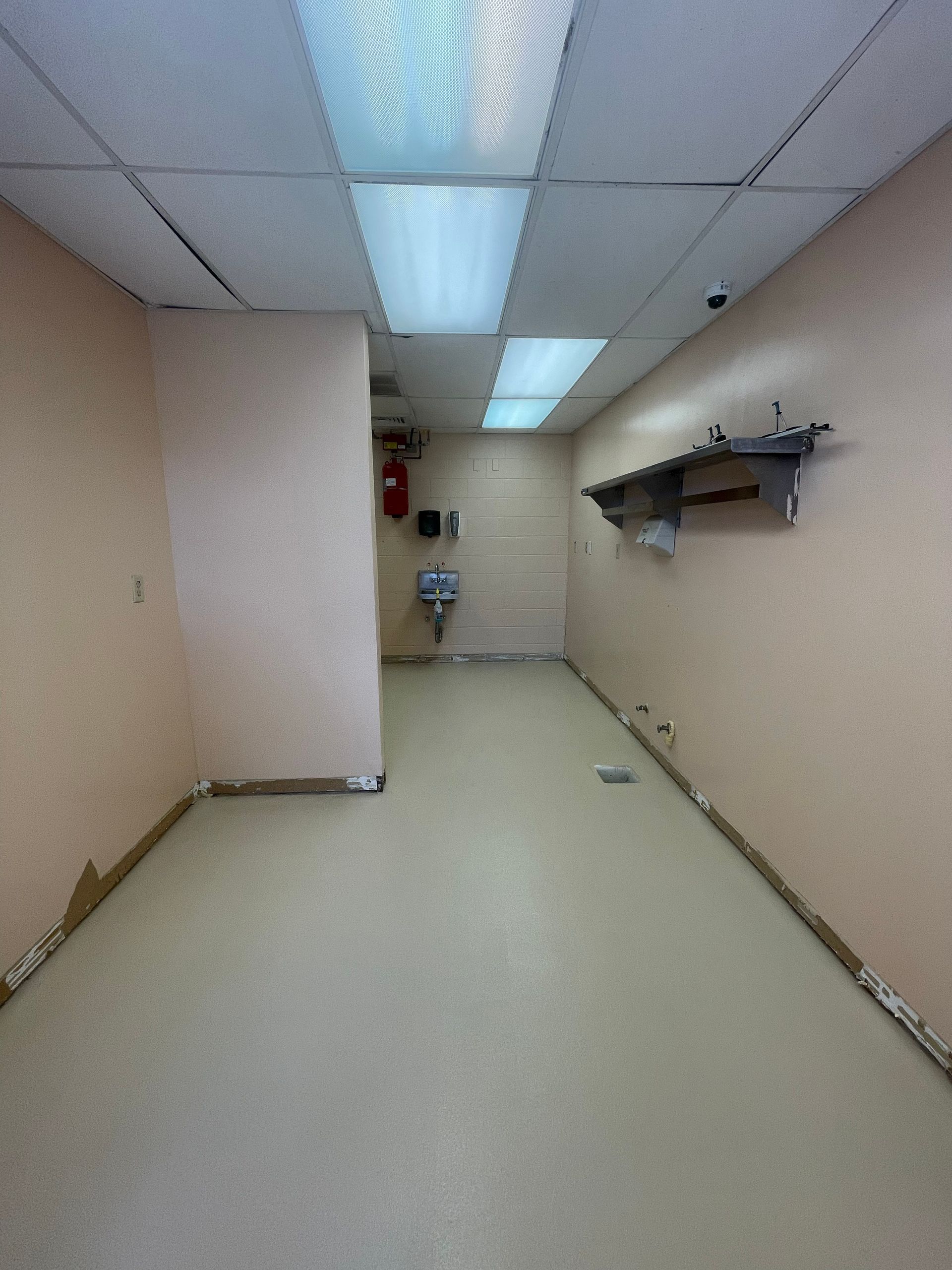 Empty beige hallway with fluorescent ceiling lights and wall-mounted shelves