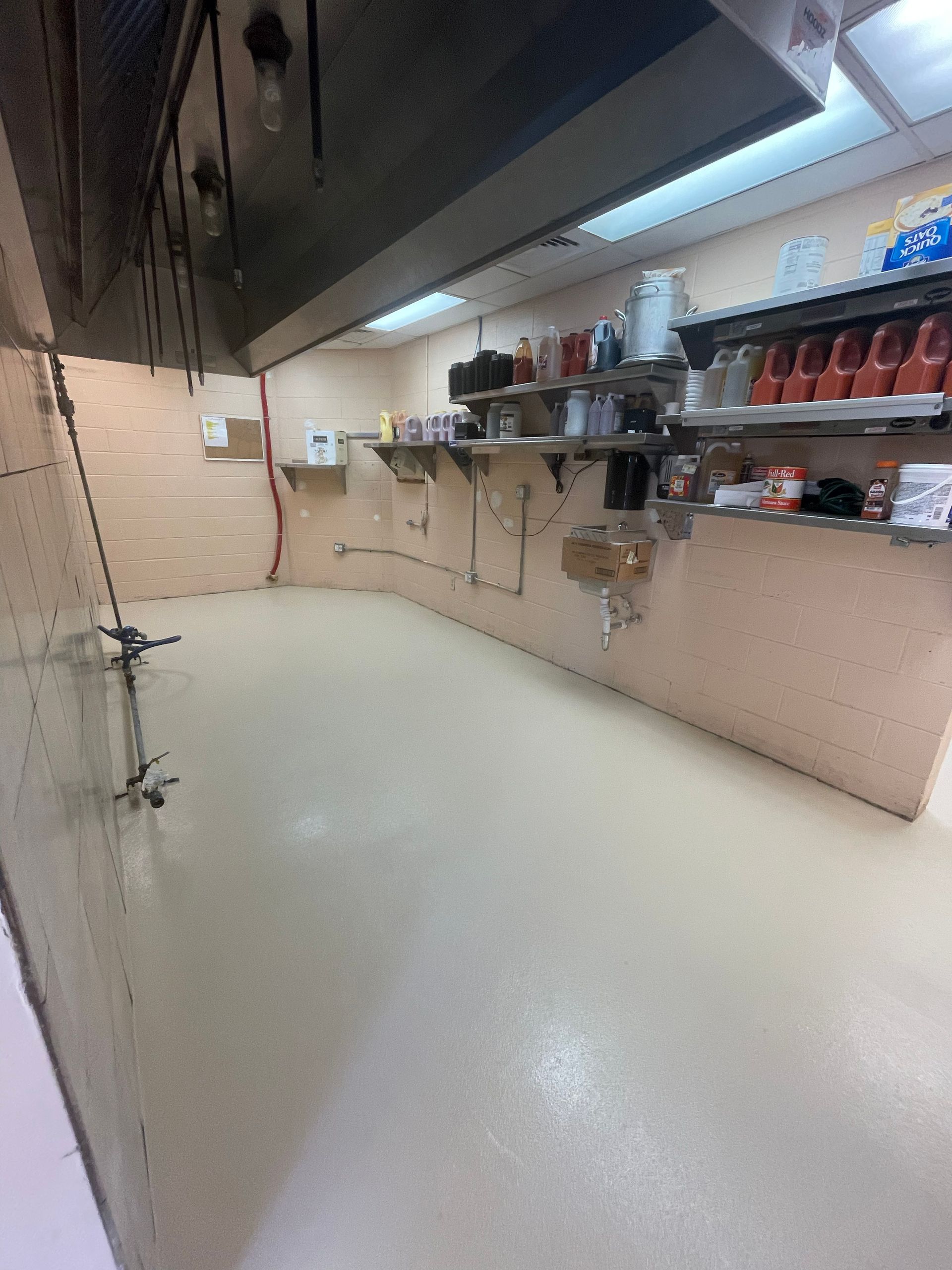 Empty industrial kitchen with stainless shelves, beige walls, and a polished floor