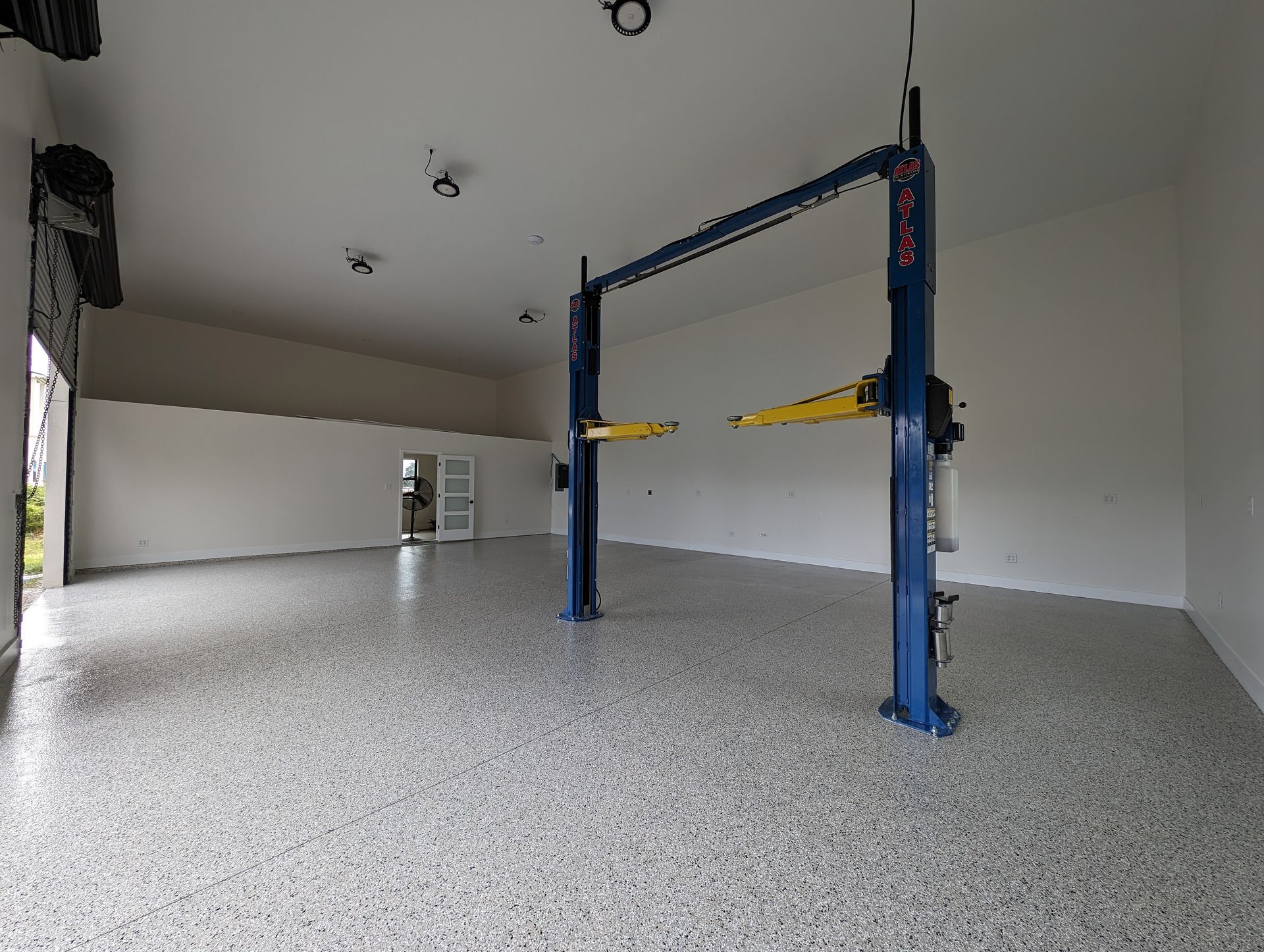 Empty garage interior with speckled floor and blue car lift supports