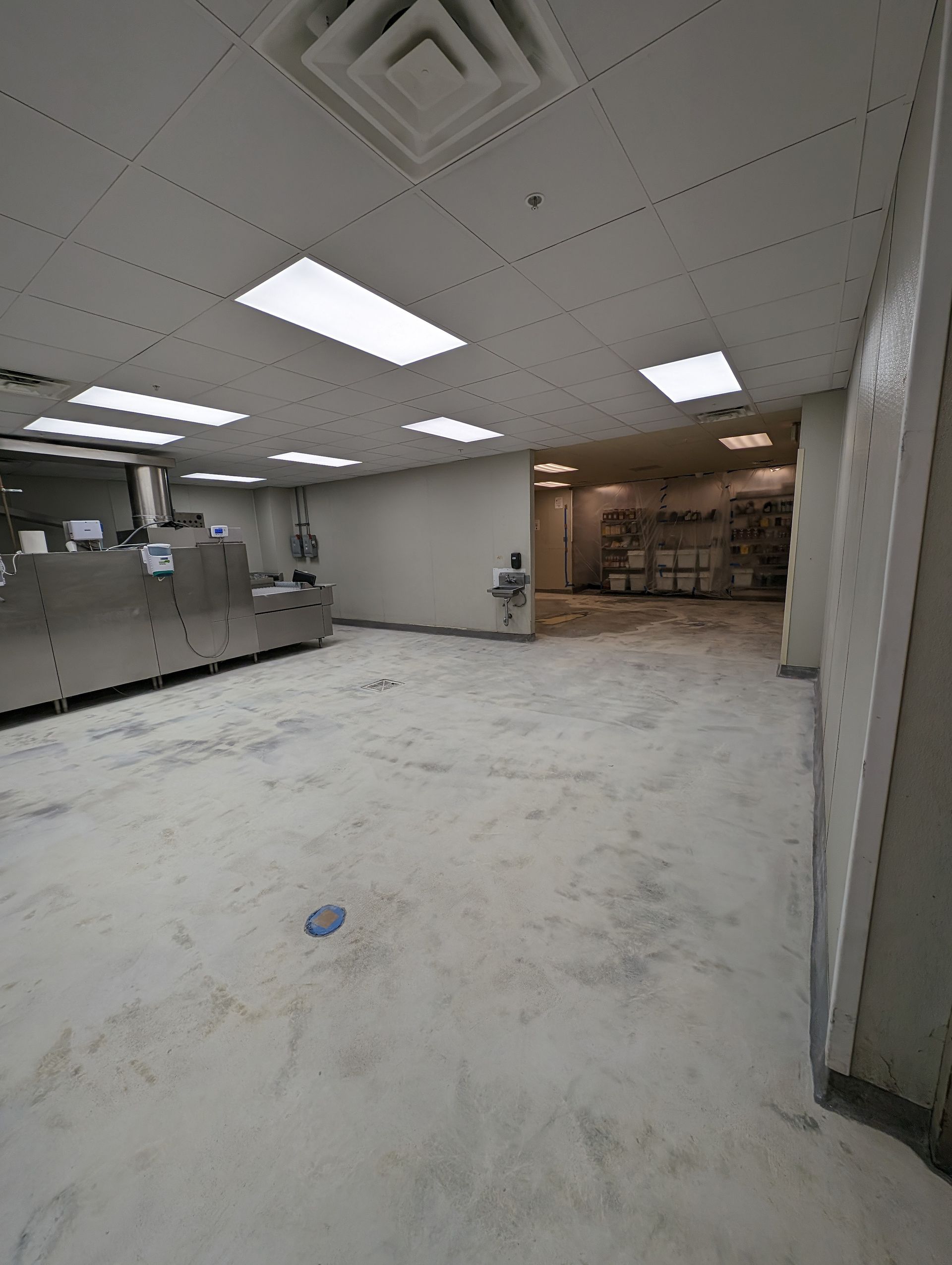 Empty office room with white ceiling lights, gray walls, and a tiled floor