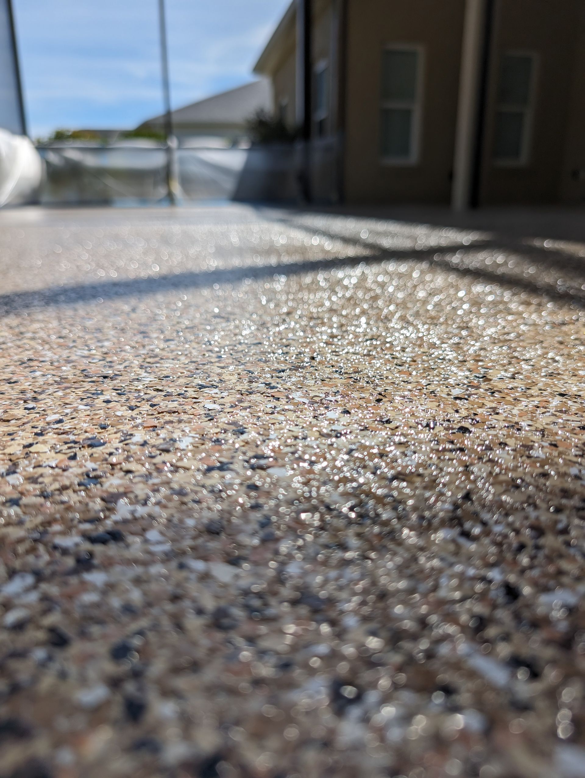 Close-up of a sunlit textured concrete surface with a blurred building and street in the background