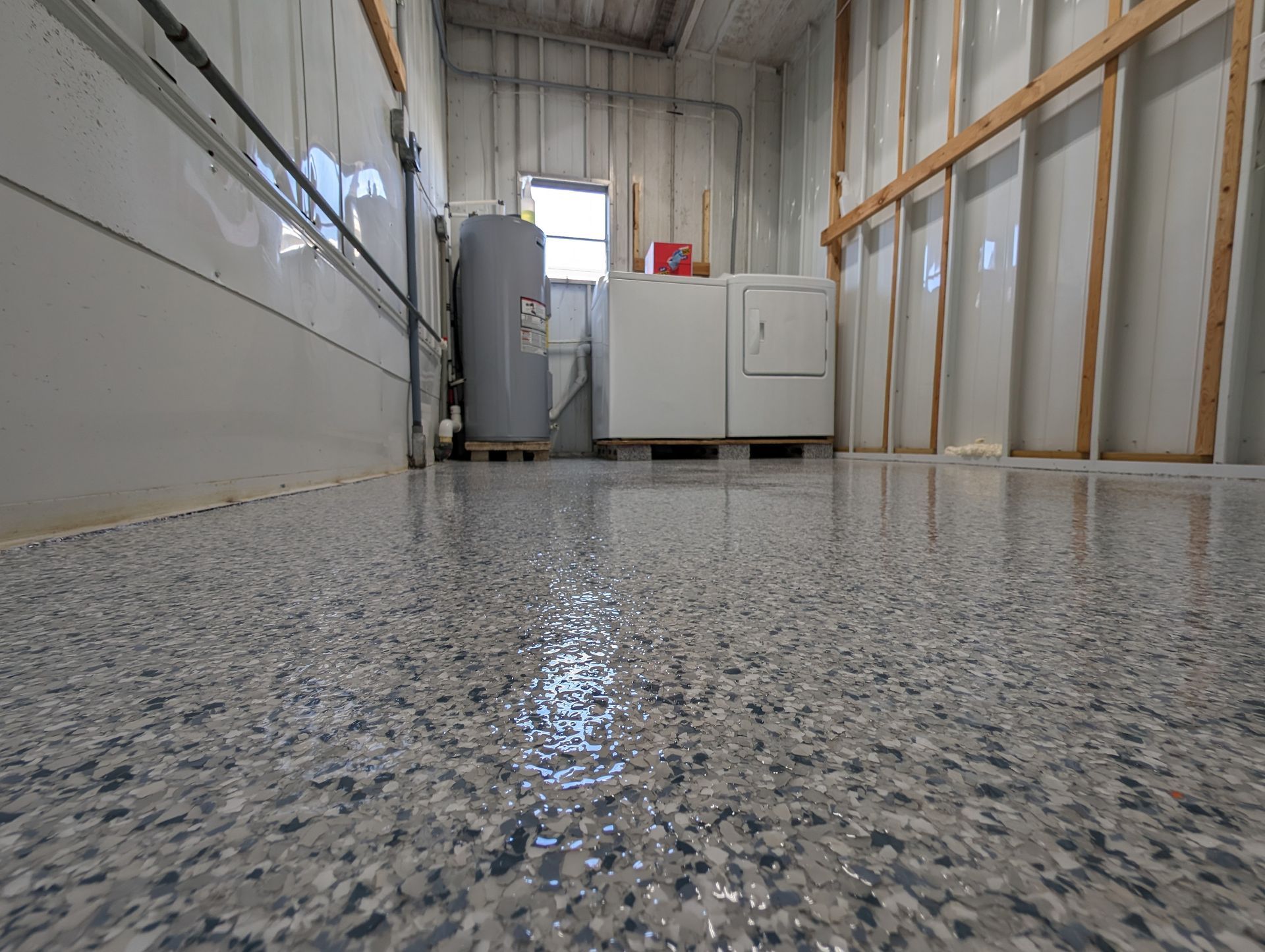 Empty industrial room with speckled epoxy floor and white cabinets along the wall