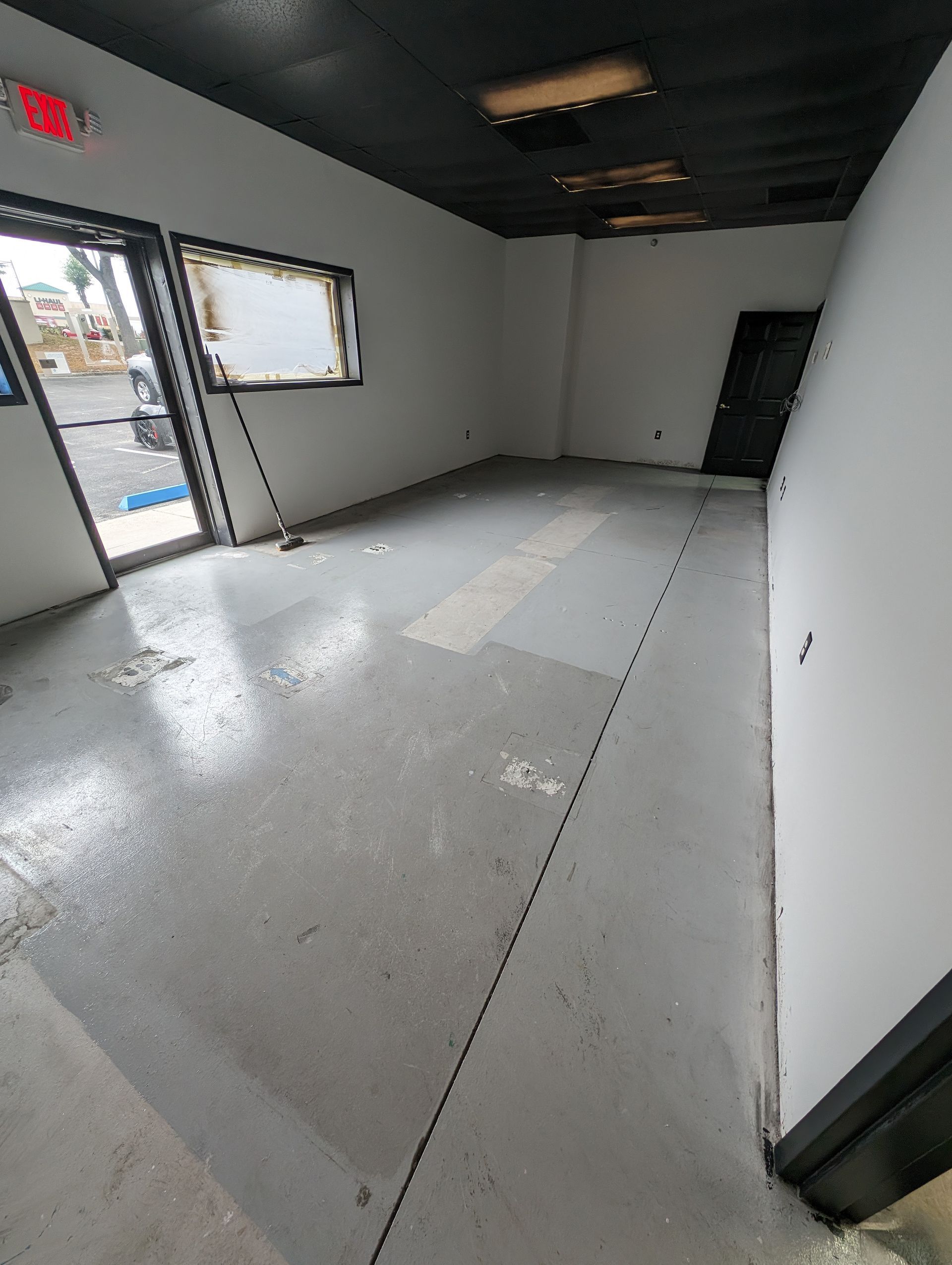 Empty unfurnished room with white walls, gray floor, and open front windows