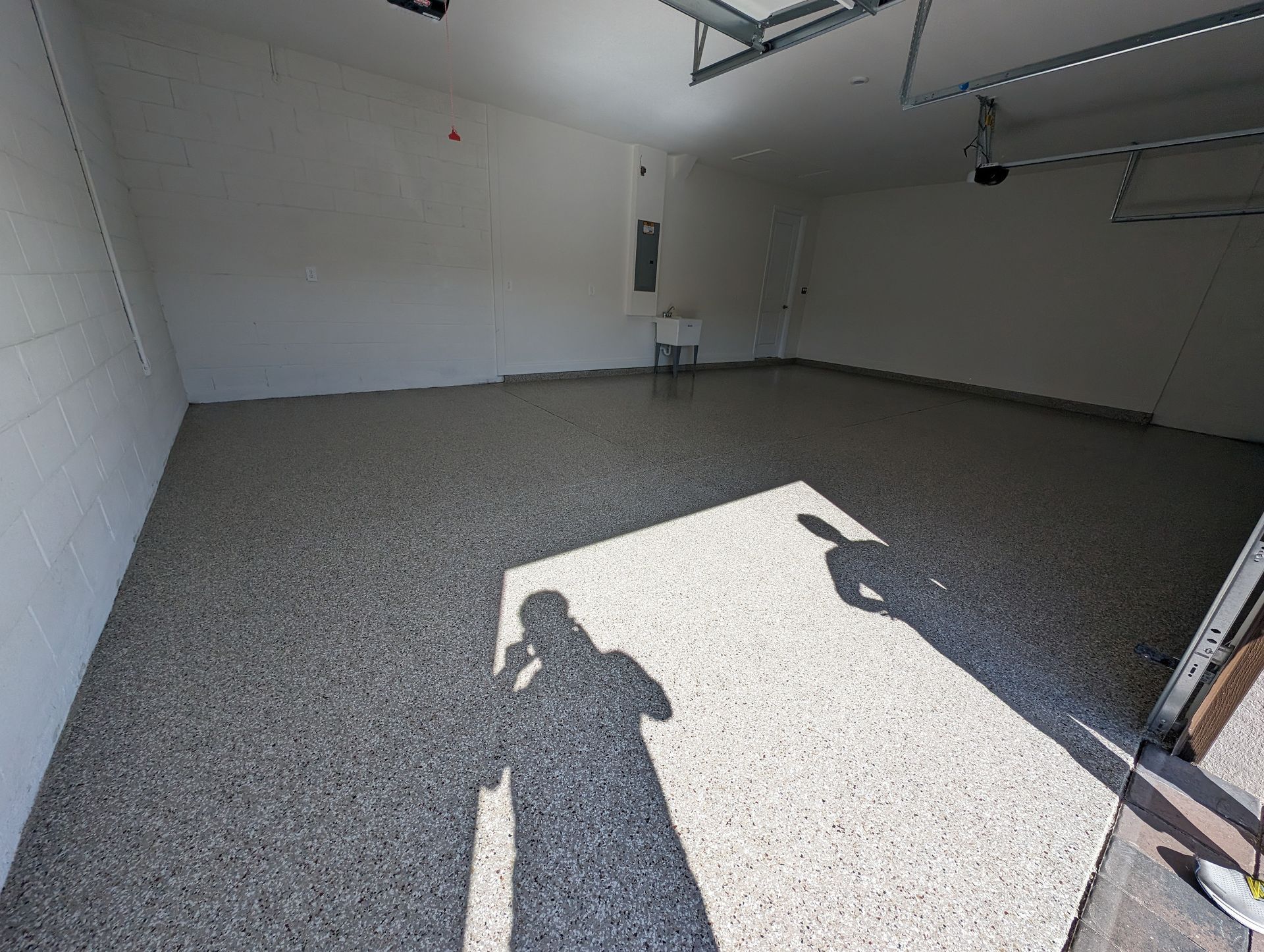 Empty garage with bright sunlight on the floor and a person's shadow near the doorway