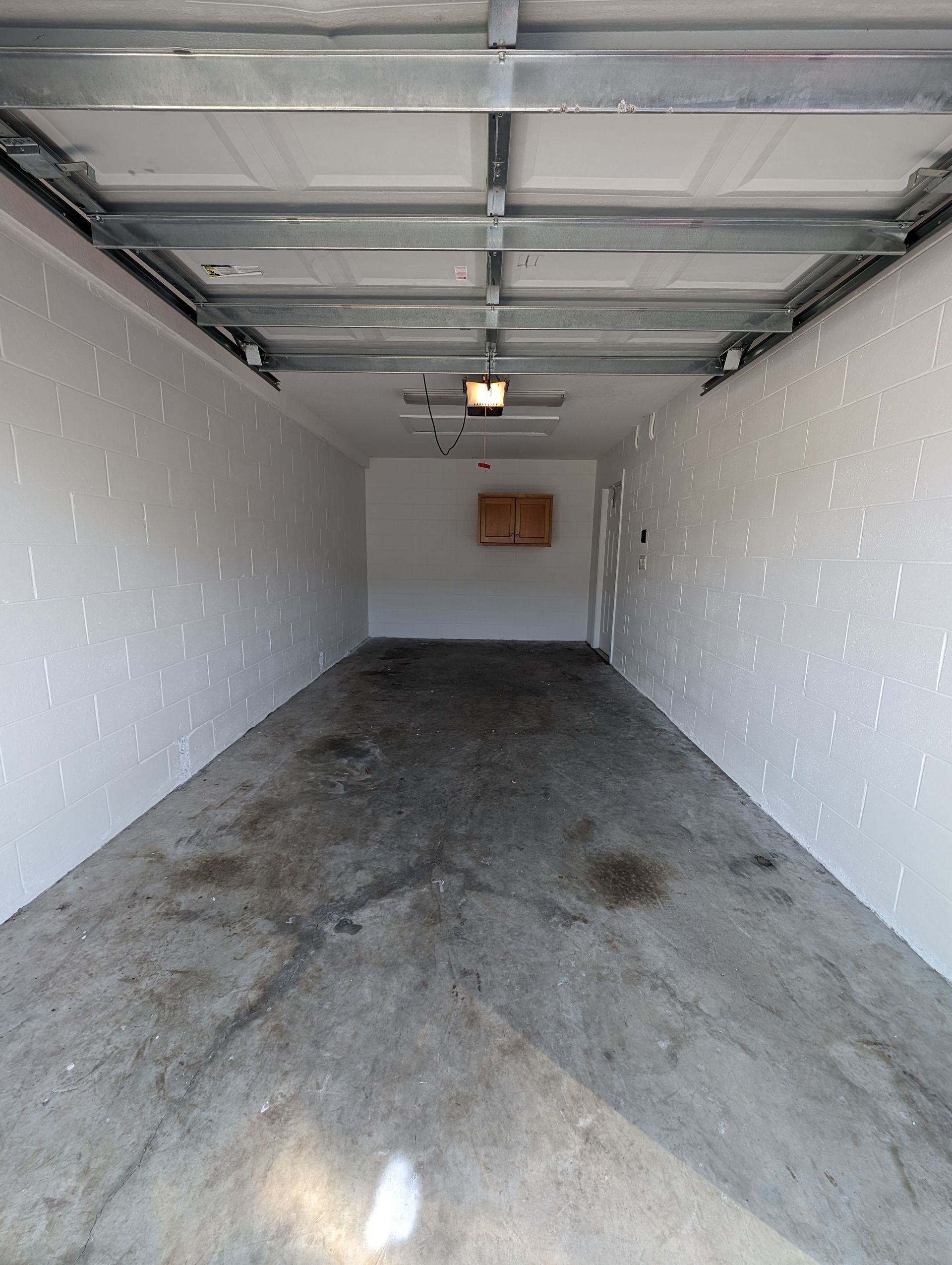 Empty single-car garage with gray concrete floor and white walls, viewed from the open doorway