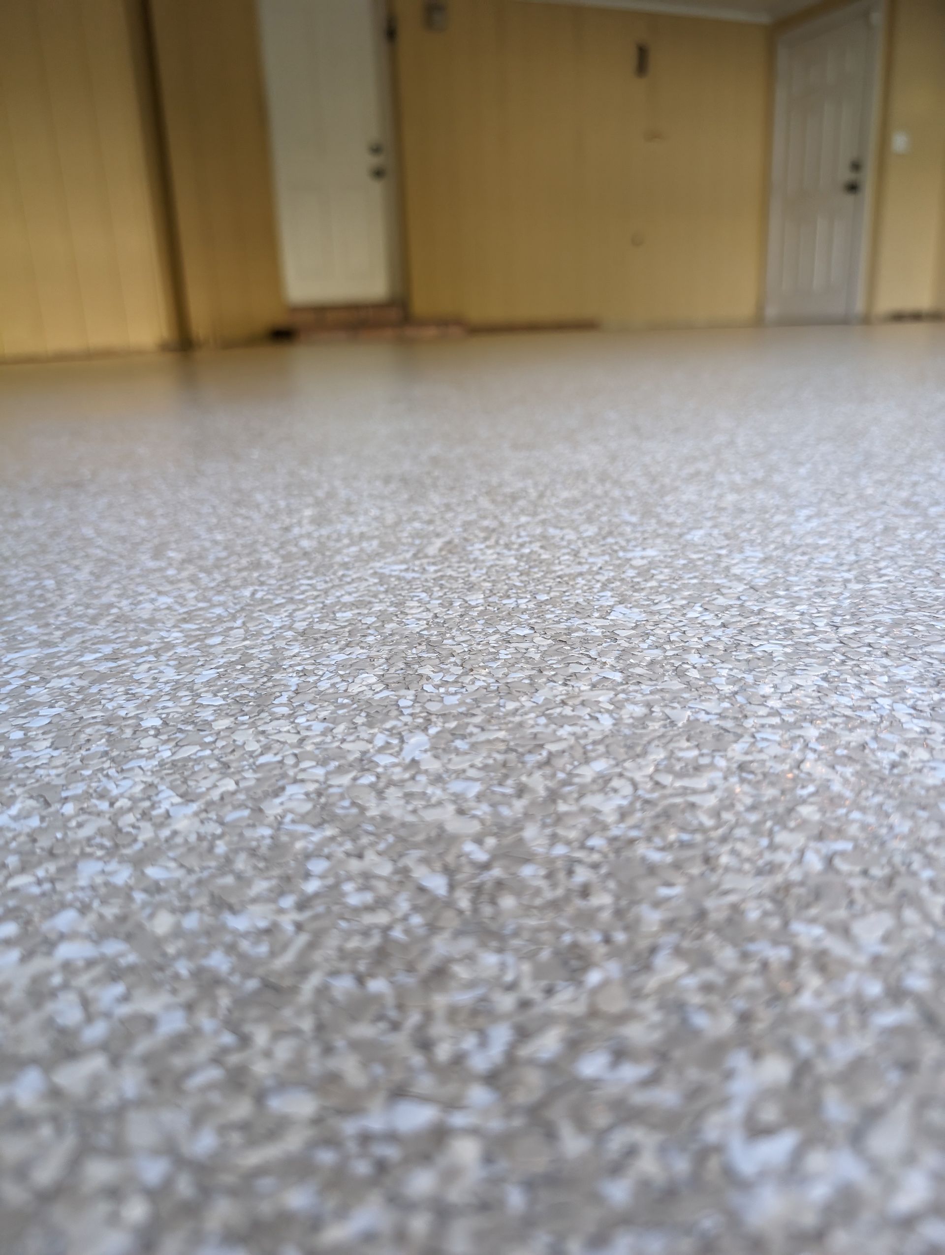 Empty room with speckled floor, wooden doors, and beige walls