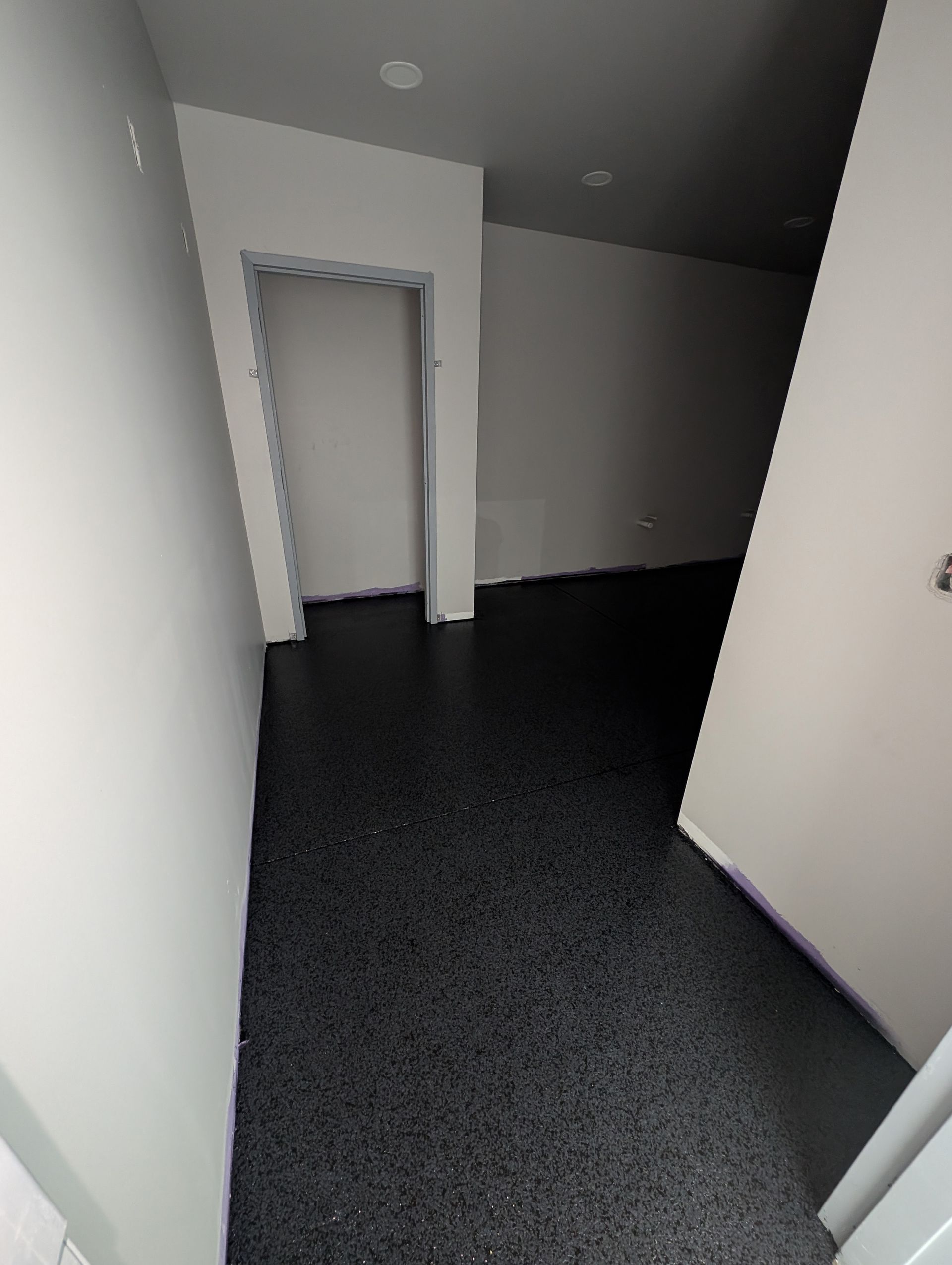 Empty hallway with white walls, dark carpet, and an open doorway ahead