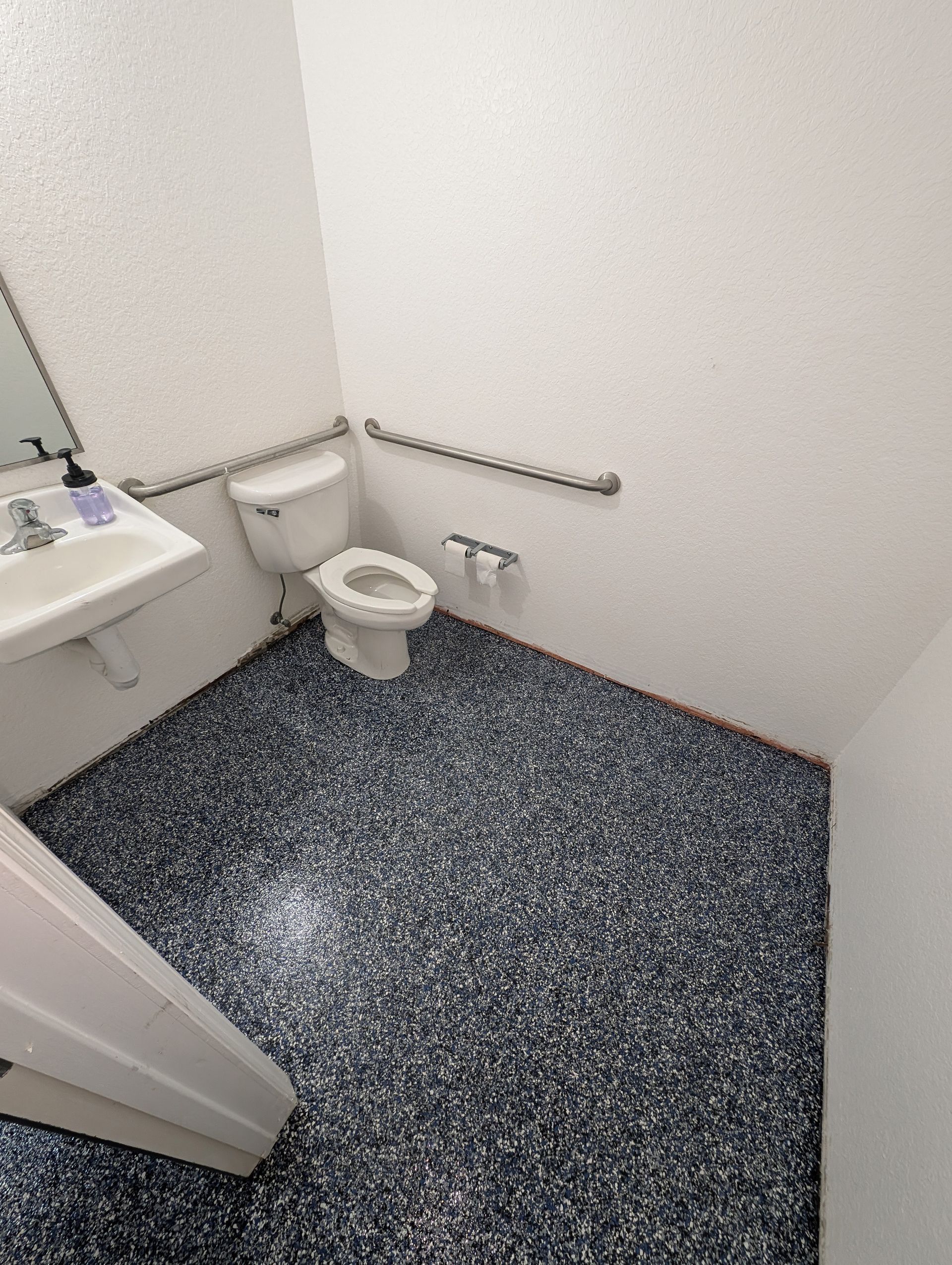Small bathroom with toilet, sink, and speckled dark floor tiles.