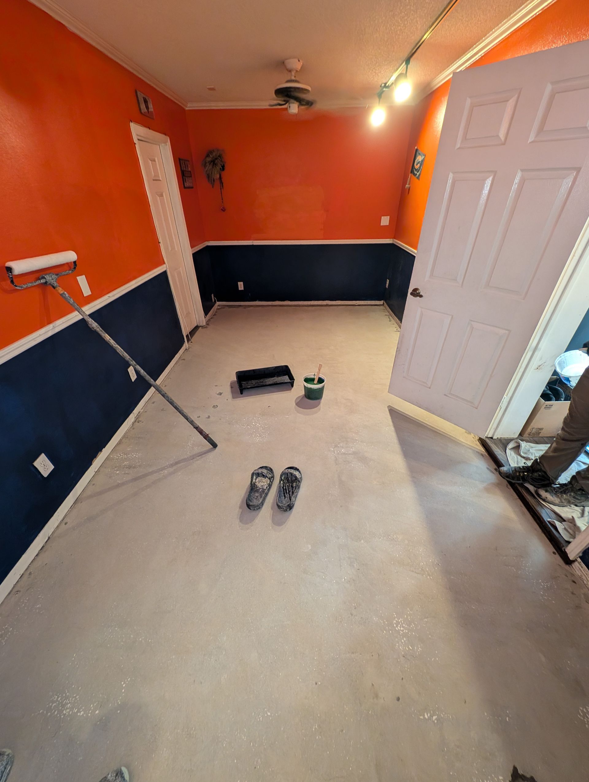 Orange and navy room under renovation with tools, shoes, and an open door on the floor