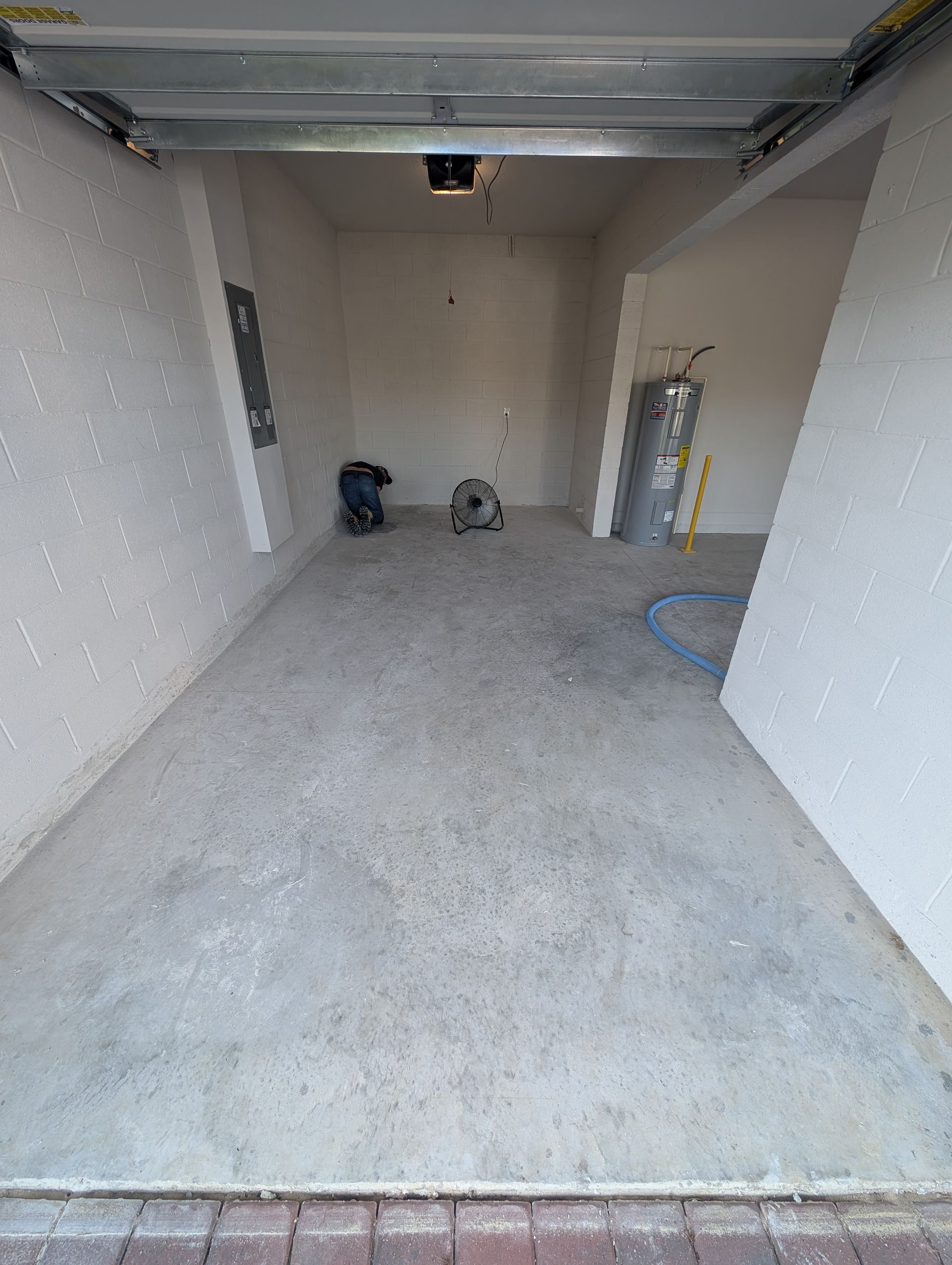 Empty unfinished garage with concrete floor, white walls, and a few items near the back wall.