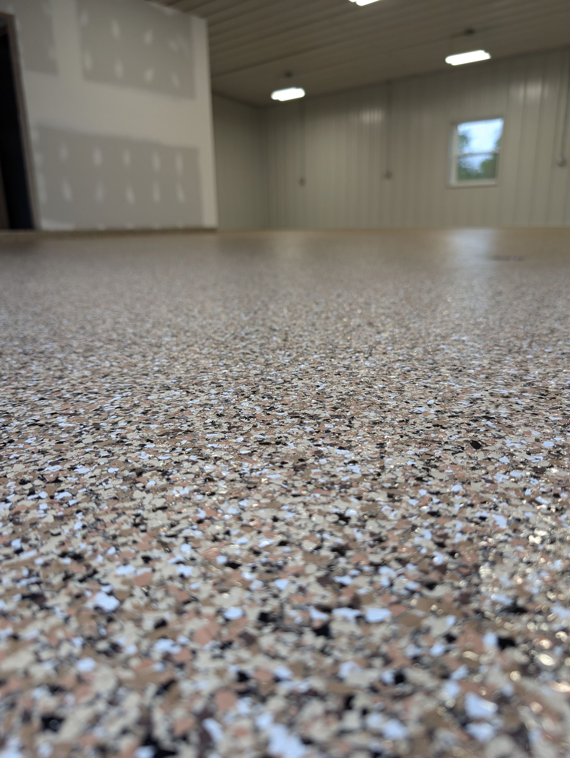 Low-angle view of a speckled epoxy floor in an empty industrial room