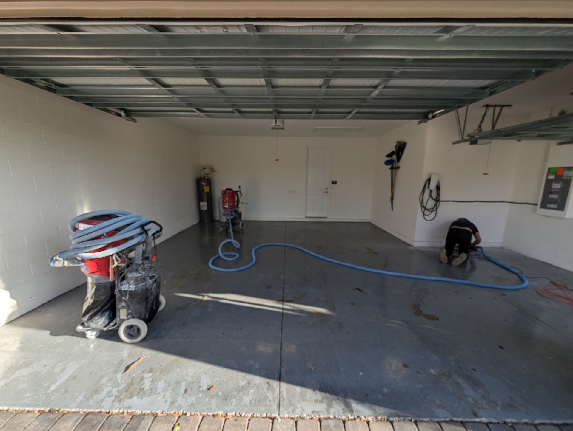 Garage interior with concrete floor, tools, and a pressure washer on the left.