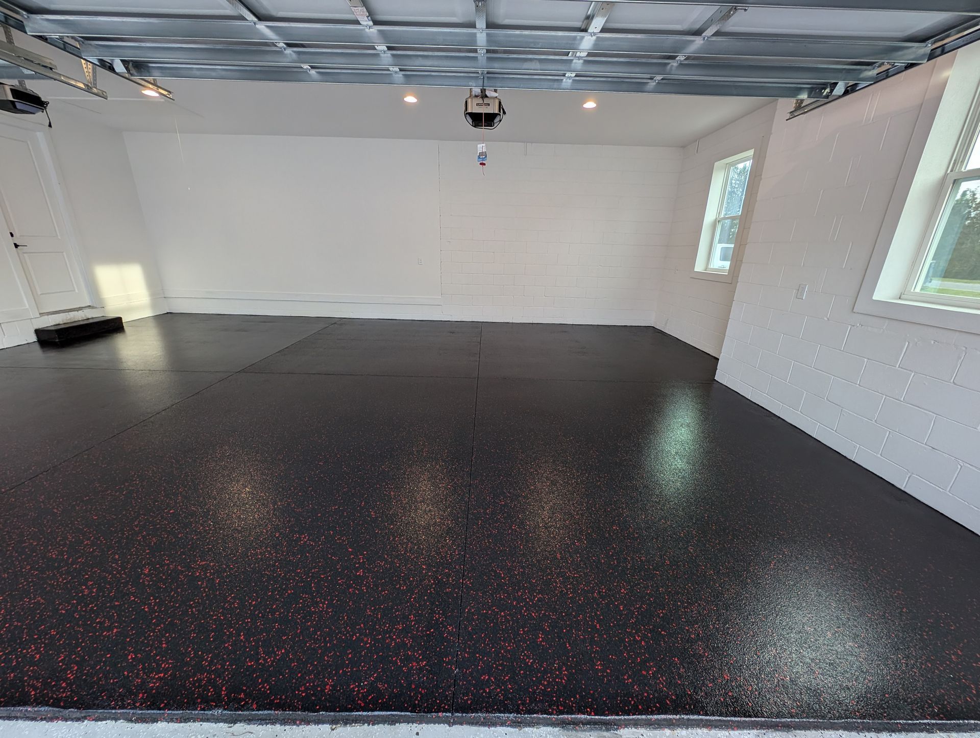 Empty garage with white walls, gray ceiling, and a glossy black speckled floor