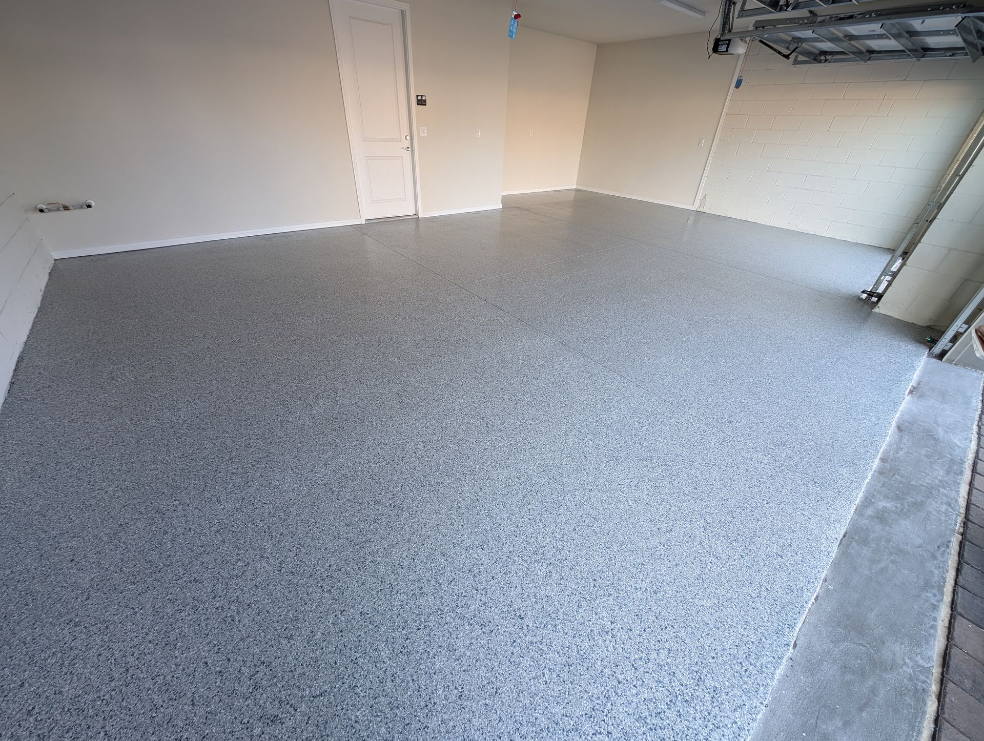 Empty room with speckled gray carpet, white walls, and shelving along the right side.