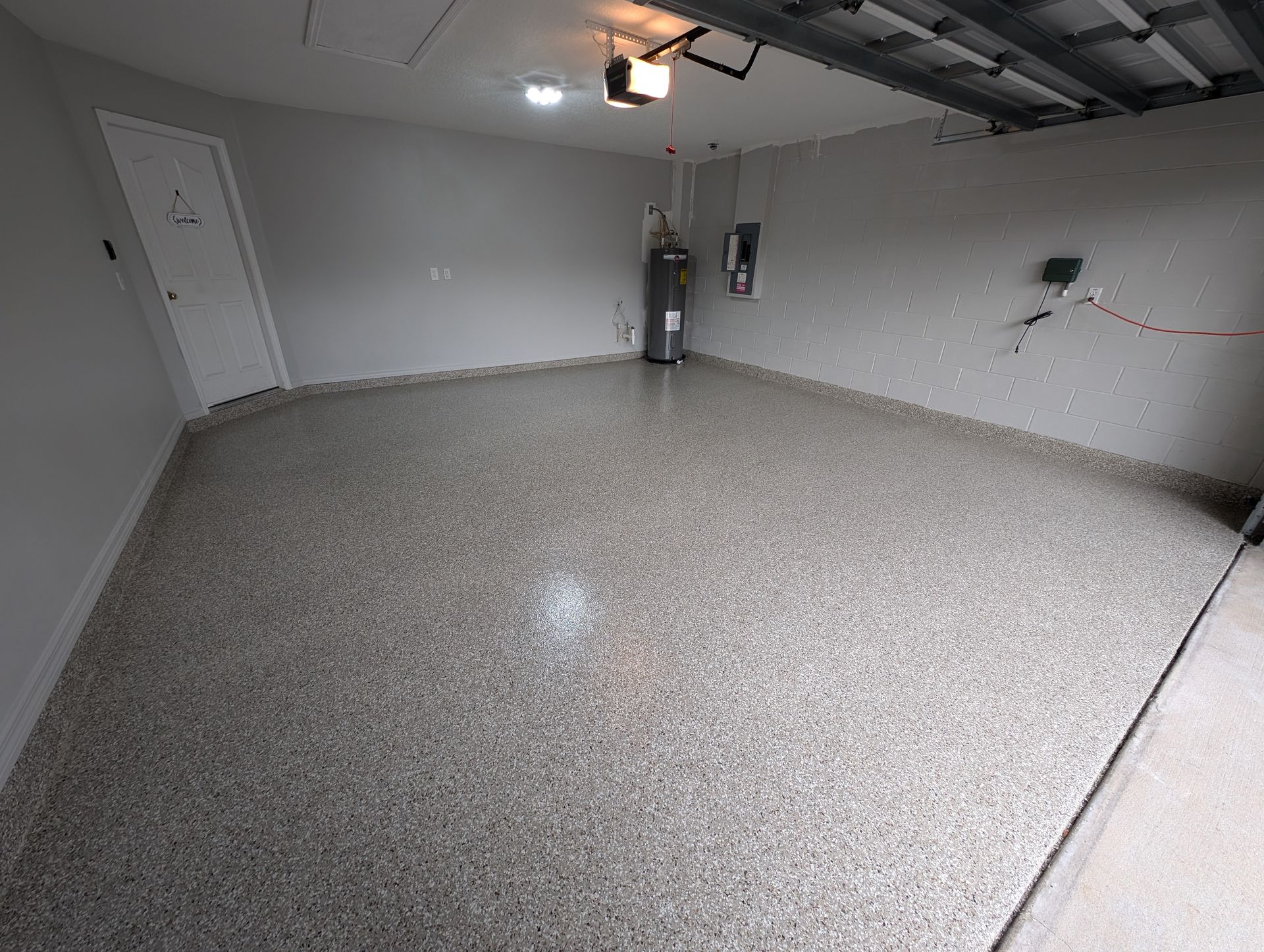 Empty gray garage with speckled floor, white walls, and a closed door.