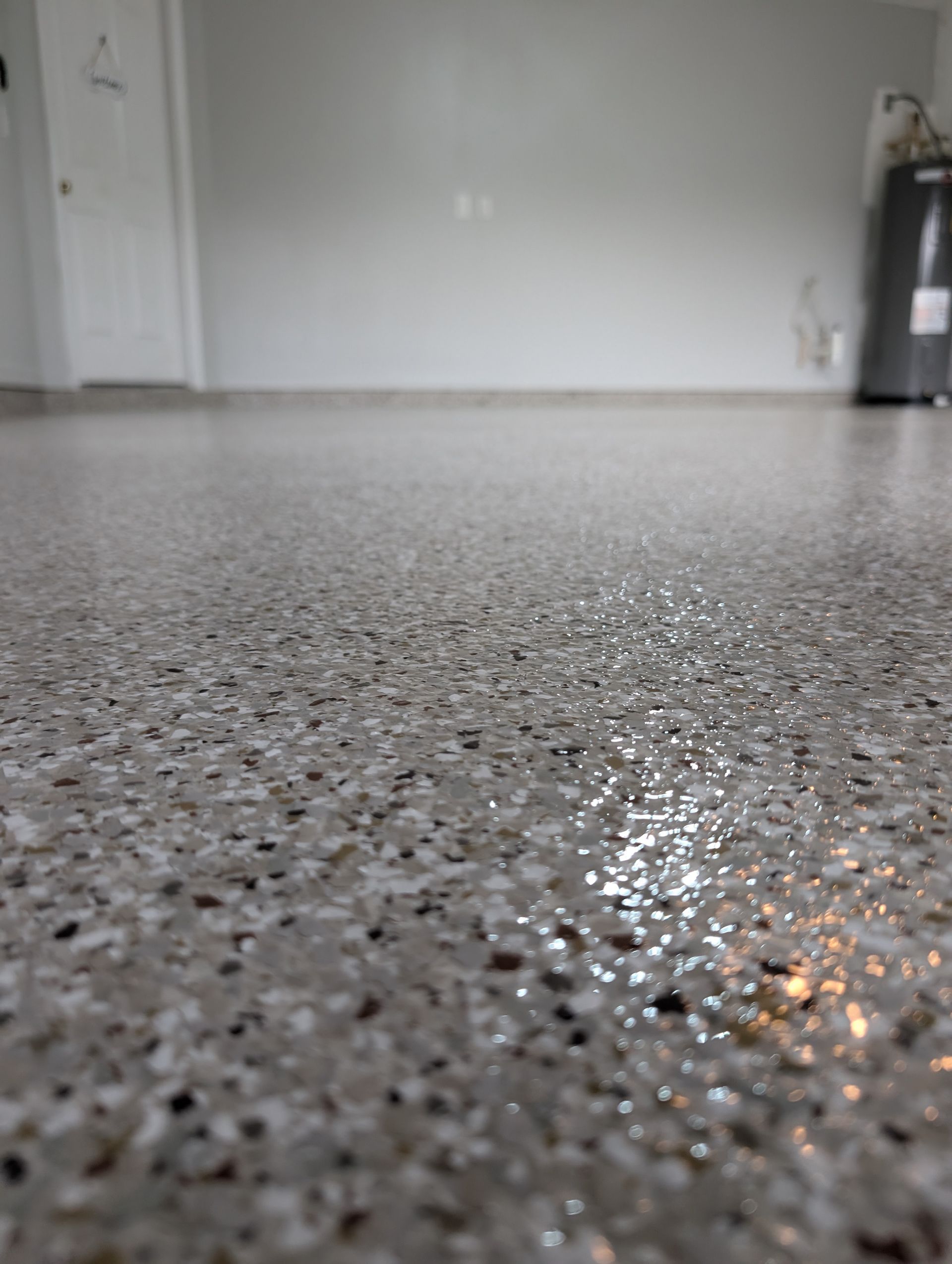Empty room with speckled gray epoxy floor and white walls, viewed from floor level