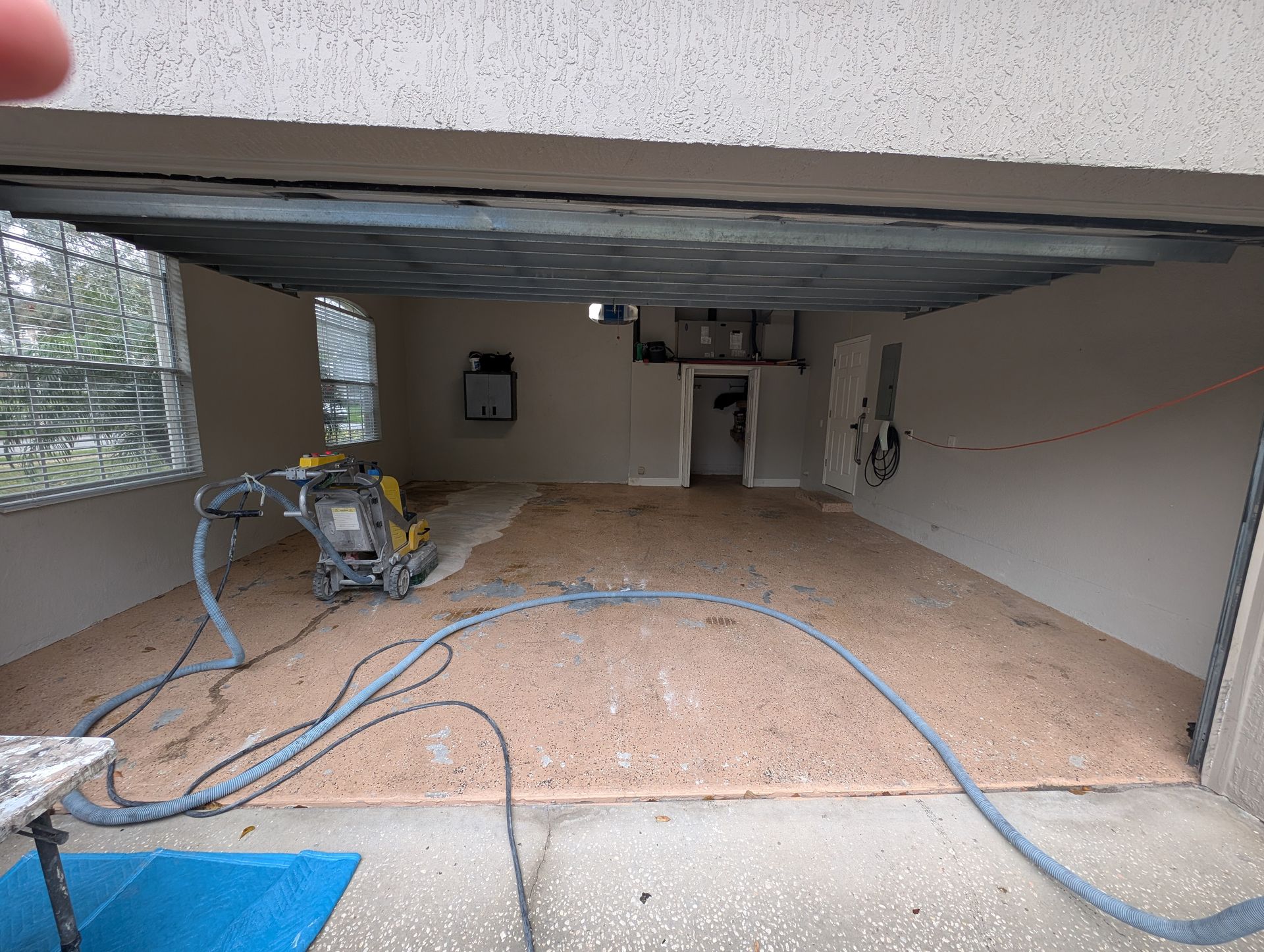 Garage under construction with exposed ceiling, tools, and blue hoses on the floor