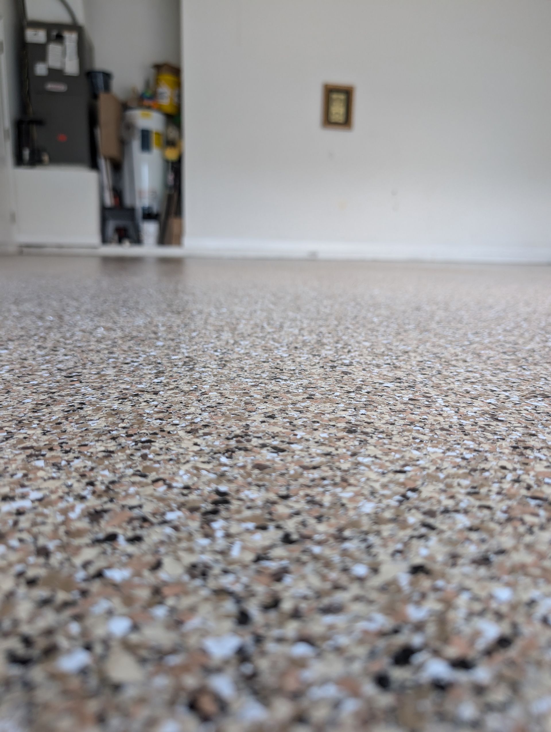 Low-angle view of a speckled carpeted floor leading to a white wall and kitchen doorway.
