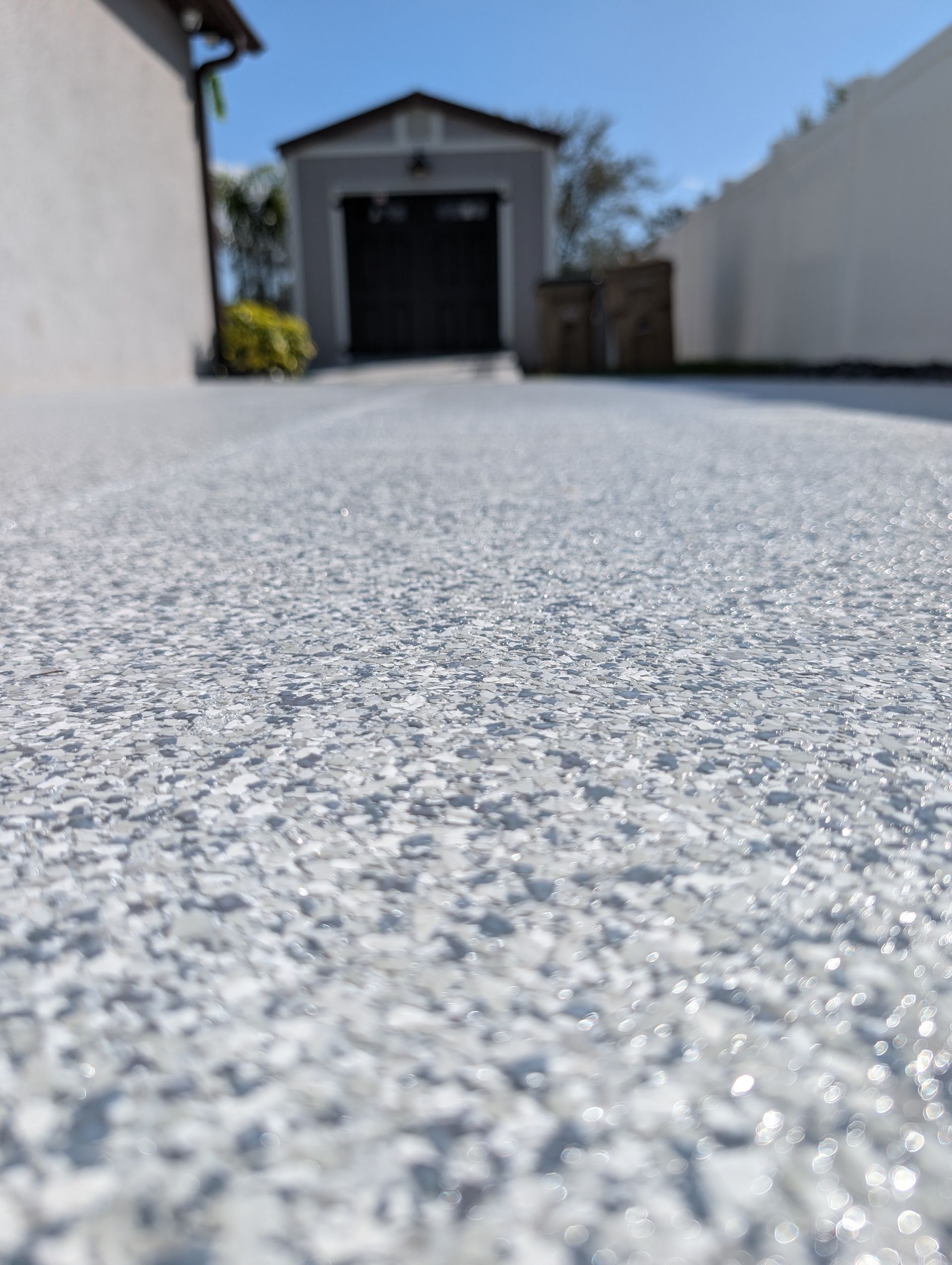 Ground-level view of a driveway leading to a garage on a sunny day
