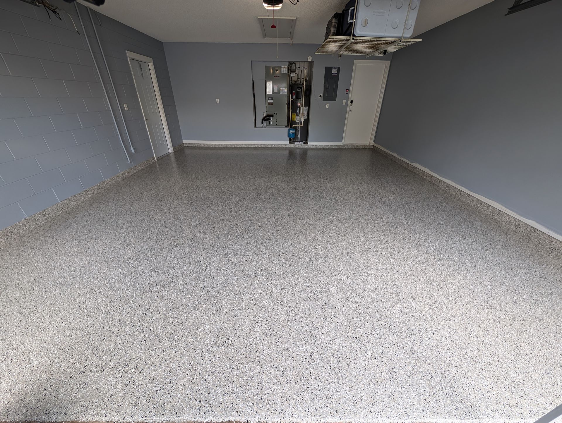 Empty gray garage with speckled floor and a person near the back wall