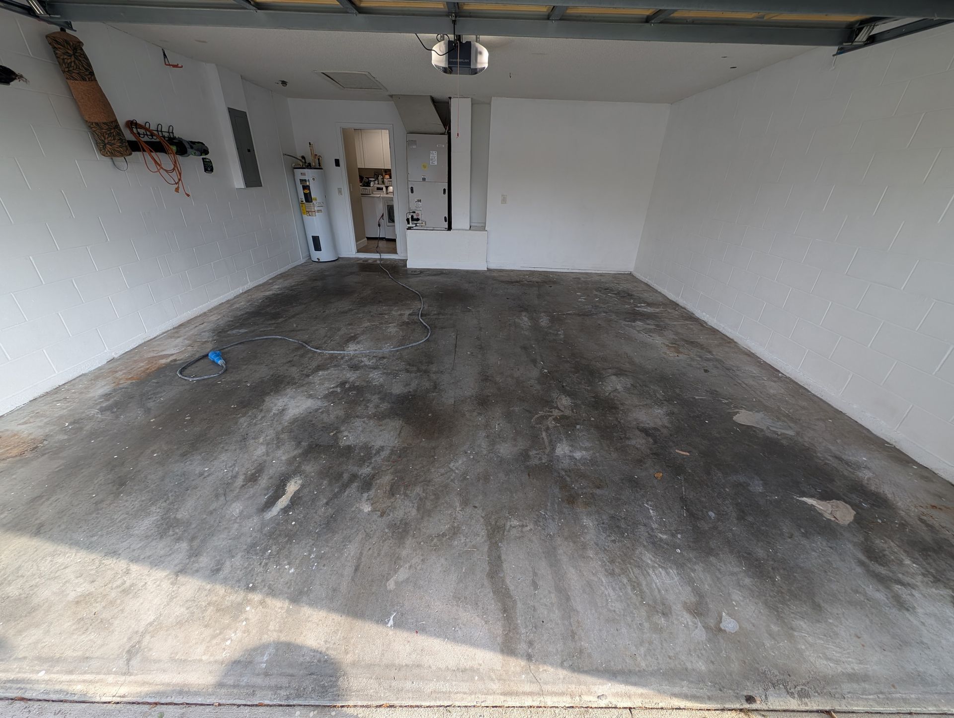 Empty garage with a stained concrete floor, white walls, and an open doorway at the back.