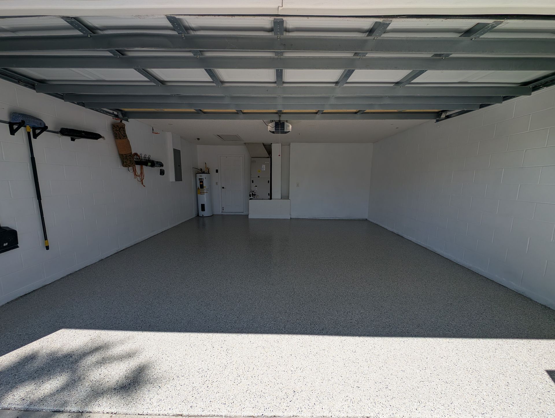 Empty two-car garage with white walls and speckled epoxy floor, viewed from the open doorway.