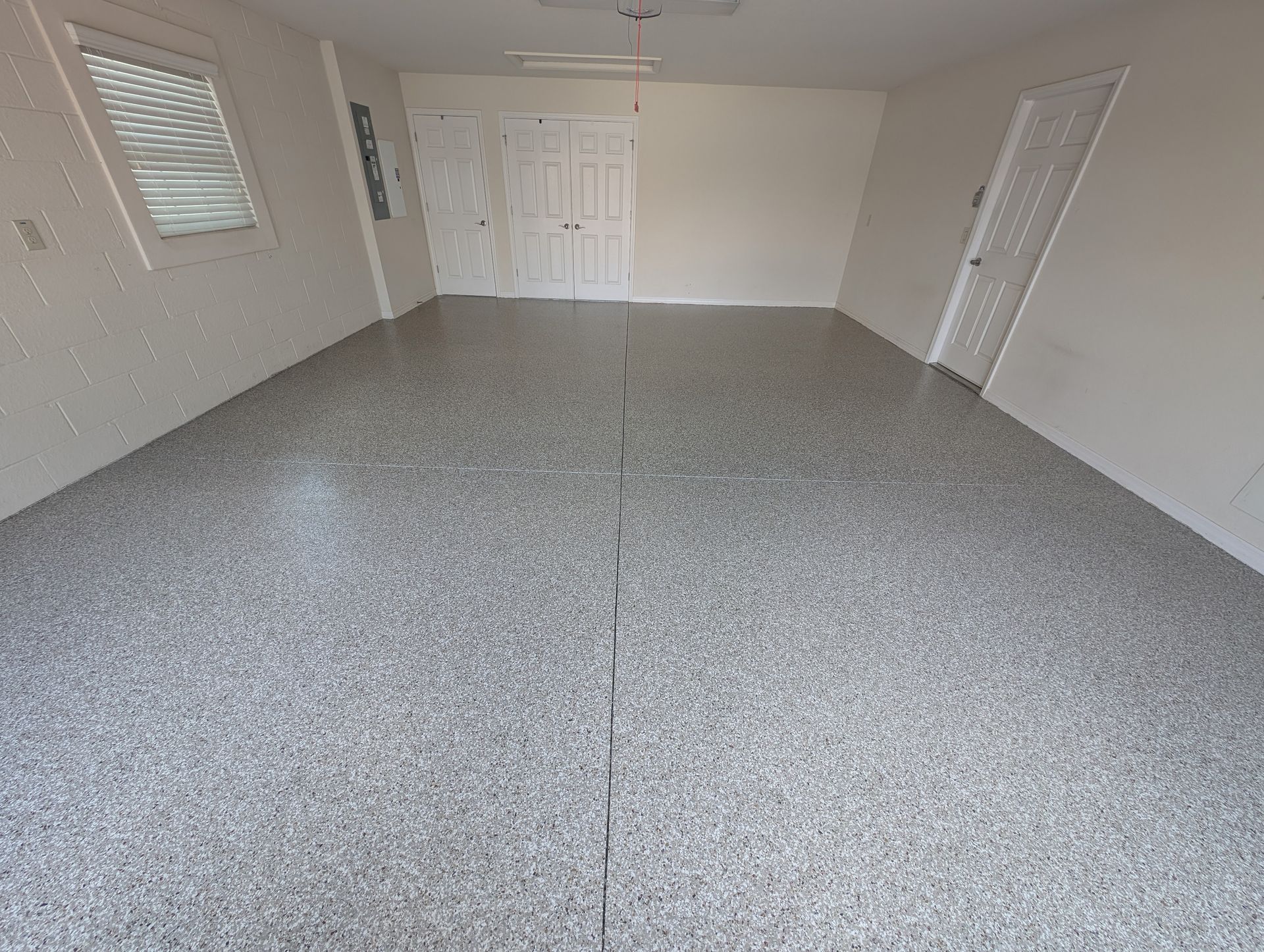 Empty carpeted living room with white walls, windows, and a closet door.