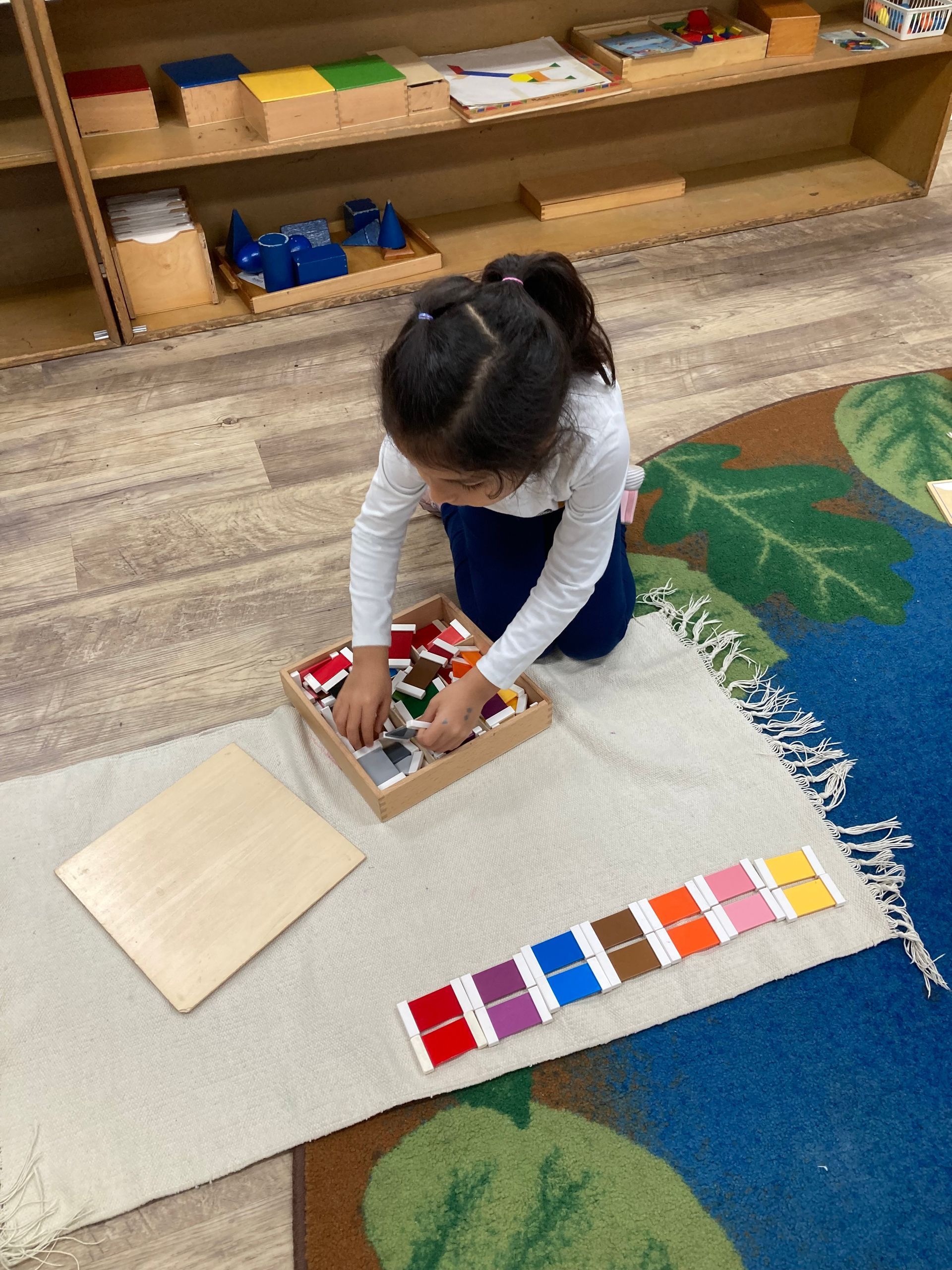 A Little Girl in an Orange Shirt is Playing With a Puzzle