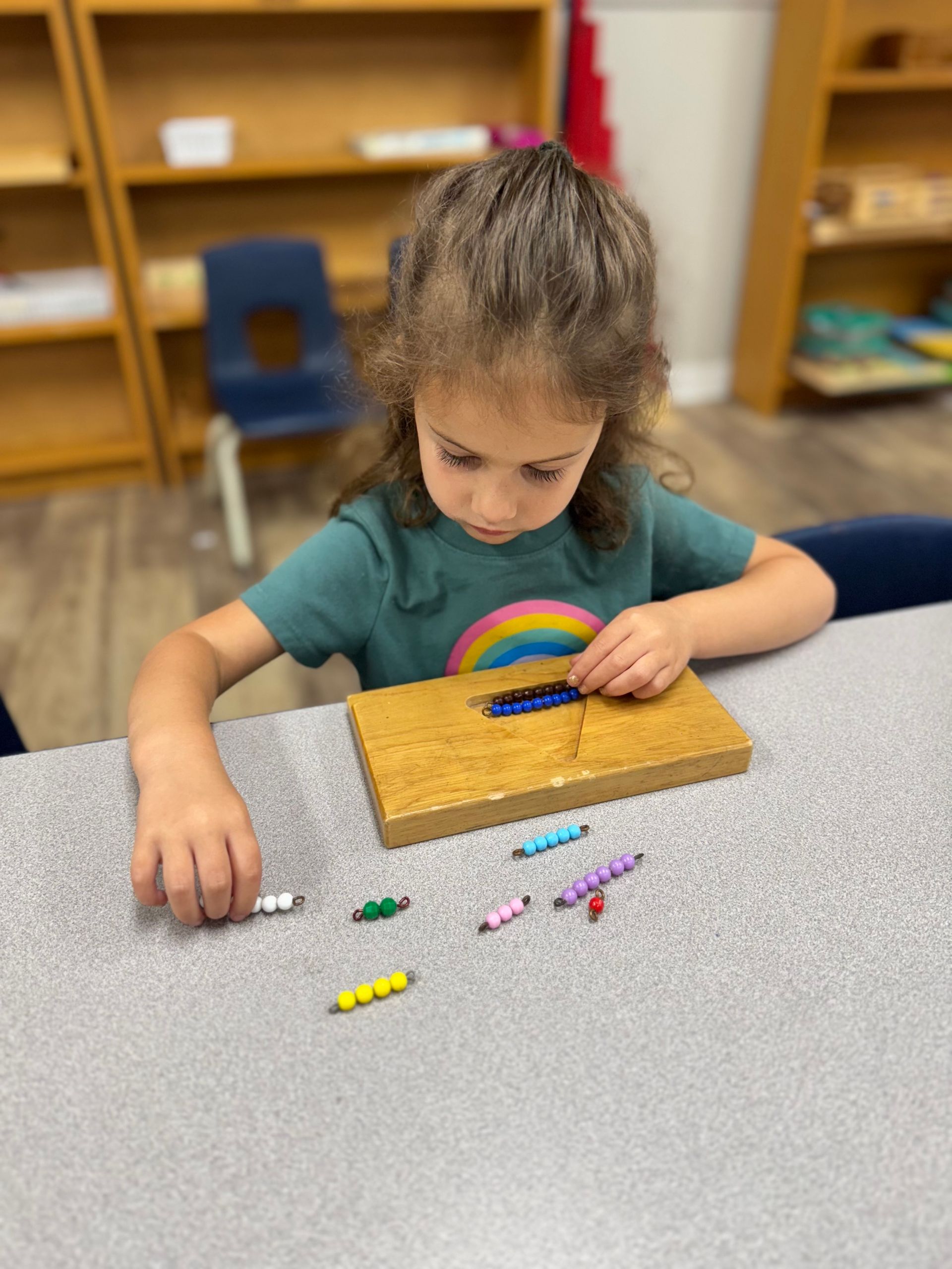 A Little Girl in an Orange Shirt is Playing With a Puzzle