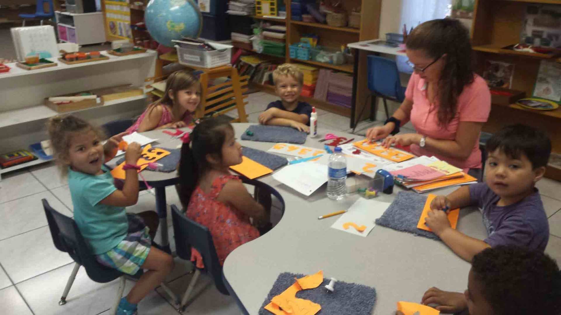 Group of Children Are Sitting Around a Table With a Teacher