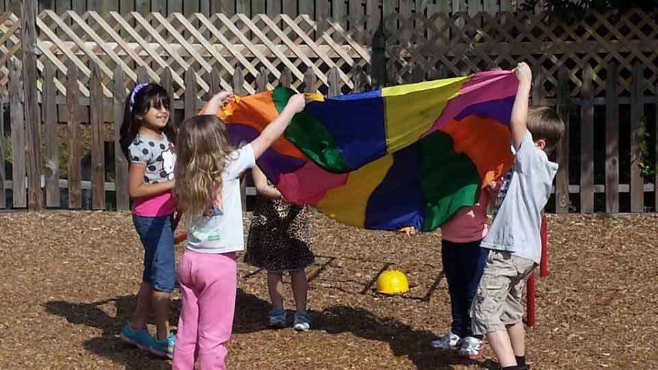 A Group of Children Are Playing With a Colorful Parachute