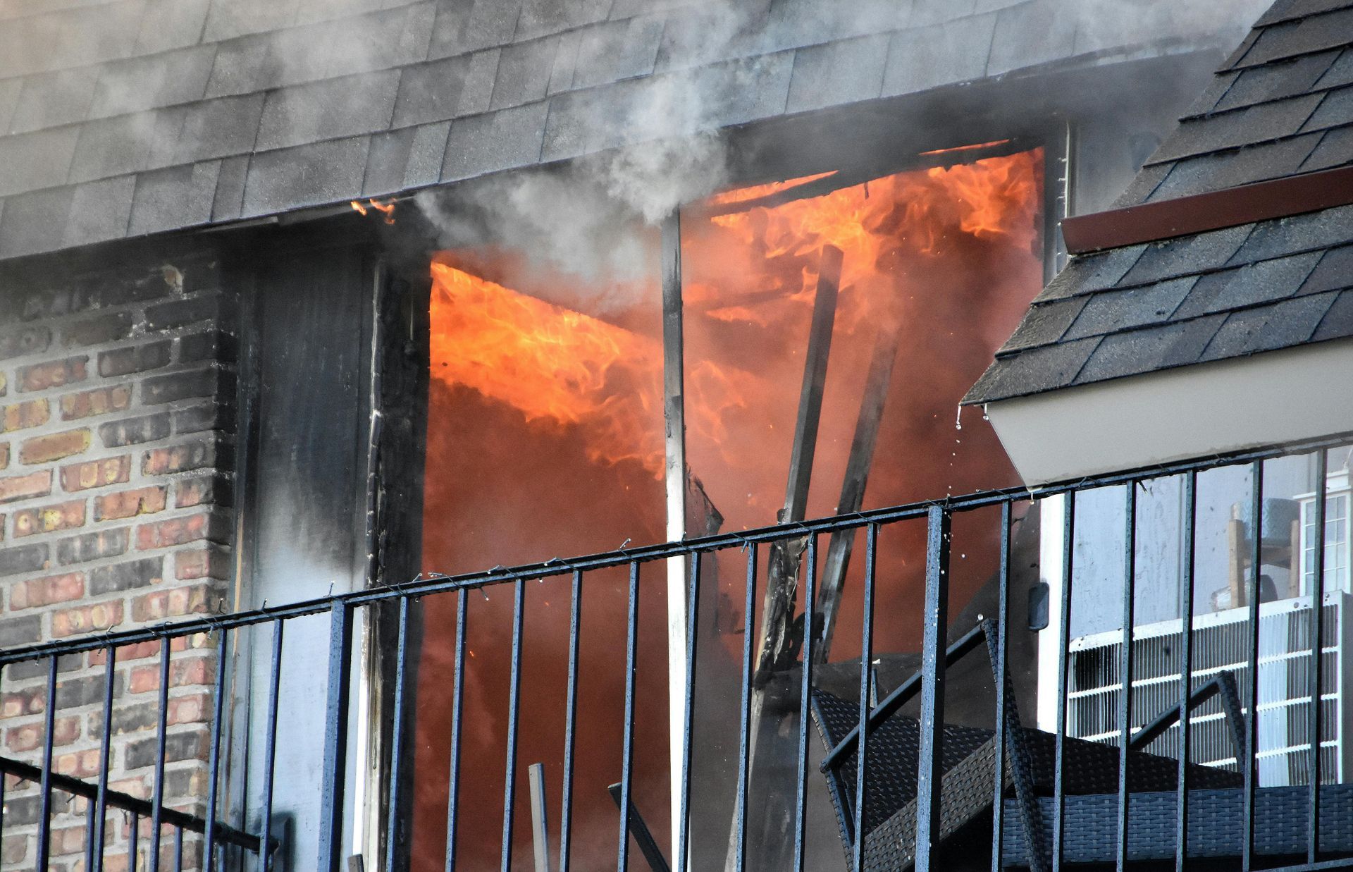 Apartment window engulfed in flames and smoke, a fire burns inside.