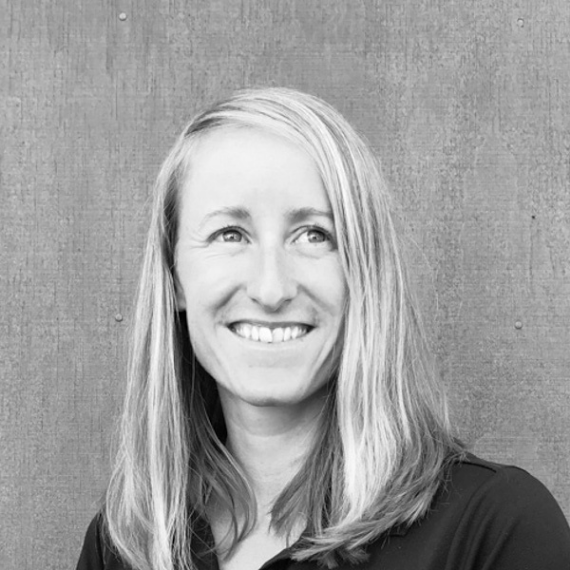 Smiling woman in a dark top against a plain gray background