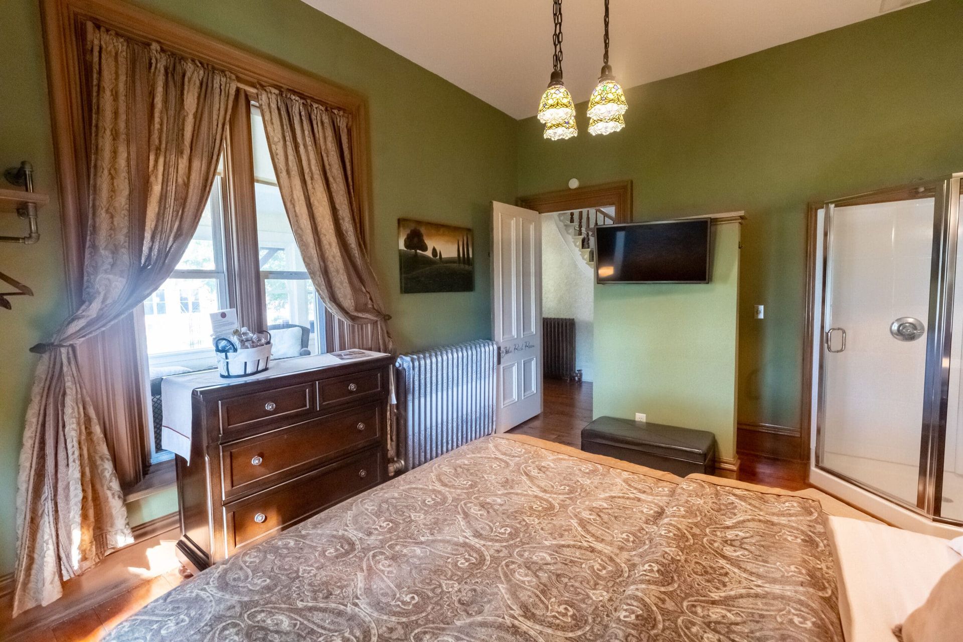 A bedroom with a king size bed , dresser , and television.