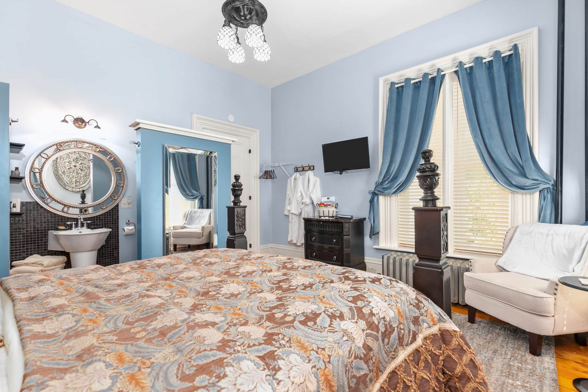 A bedroom with a bed , couch , sink and mirror.