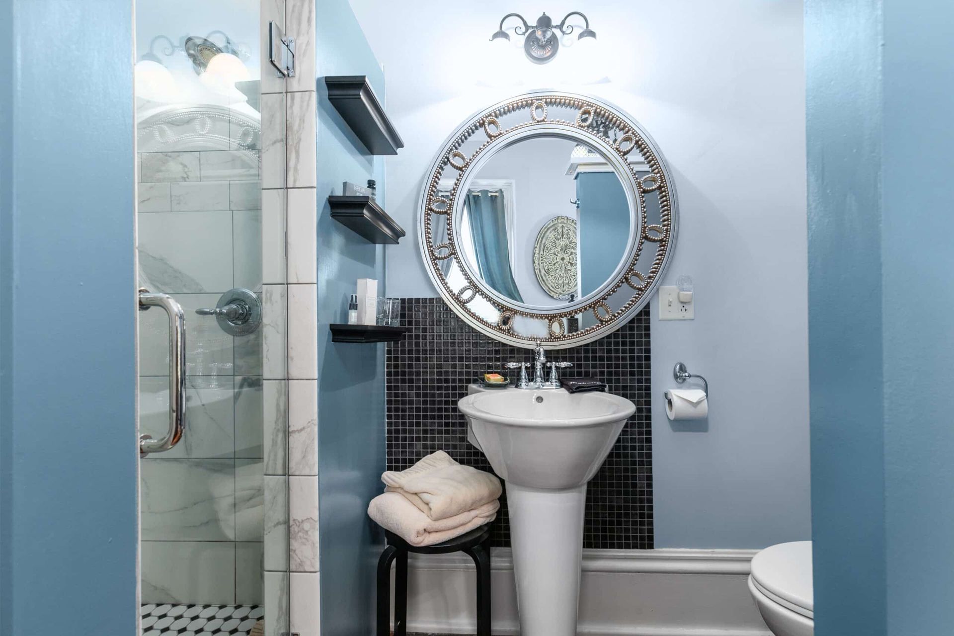 A bathroom with a sink , toilet , shower and mirror.