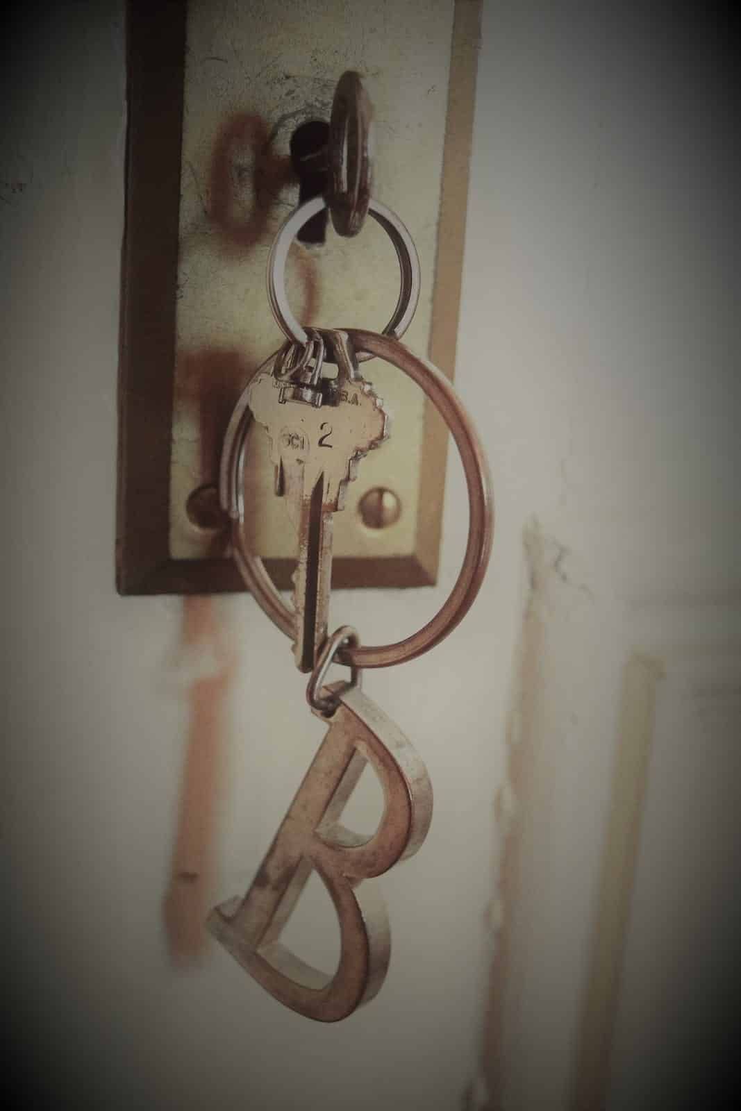 A key chain with the letter b on it is hanging on a door.