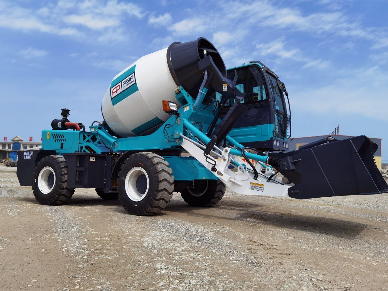Teal and white concrete mixer truck with a black bucket, parked on gravel in front of a blue sky.